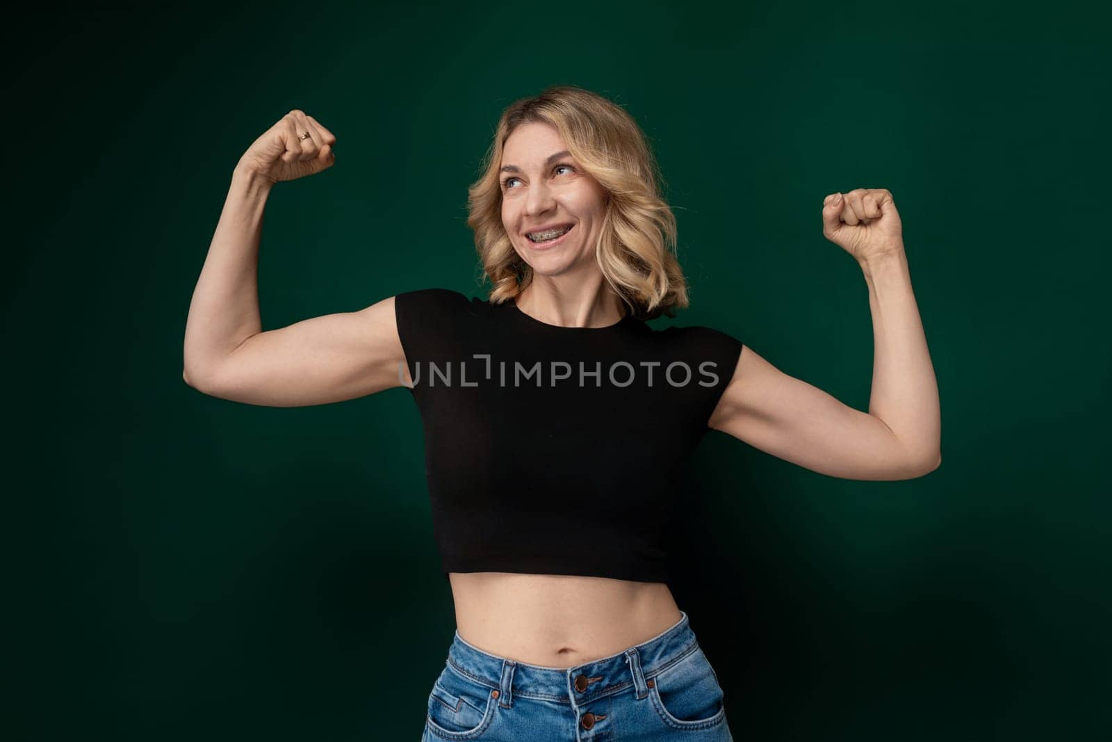 A woman stands with her arms raised above her head, striking a pose of triumph or joy. She appears confident and energetic as she holds her pose.