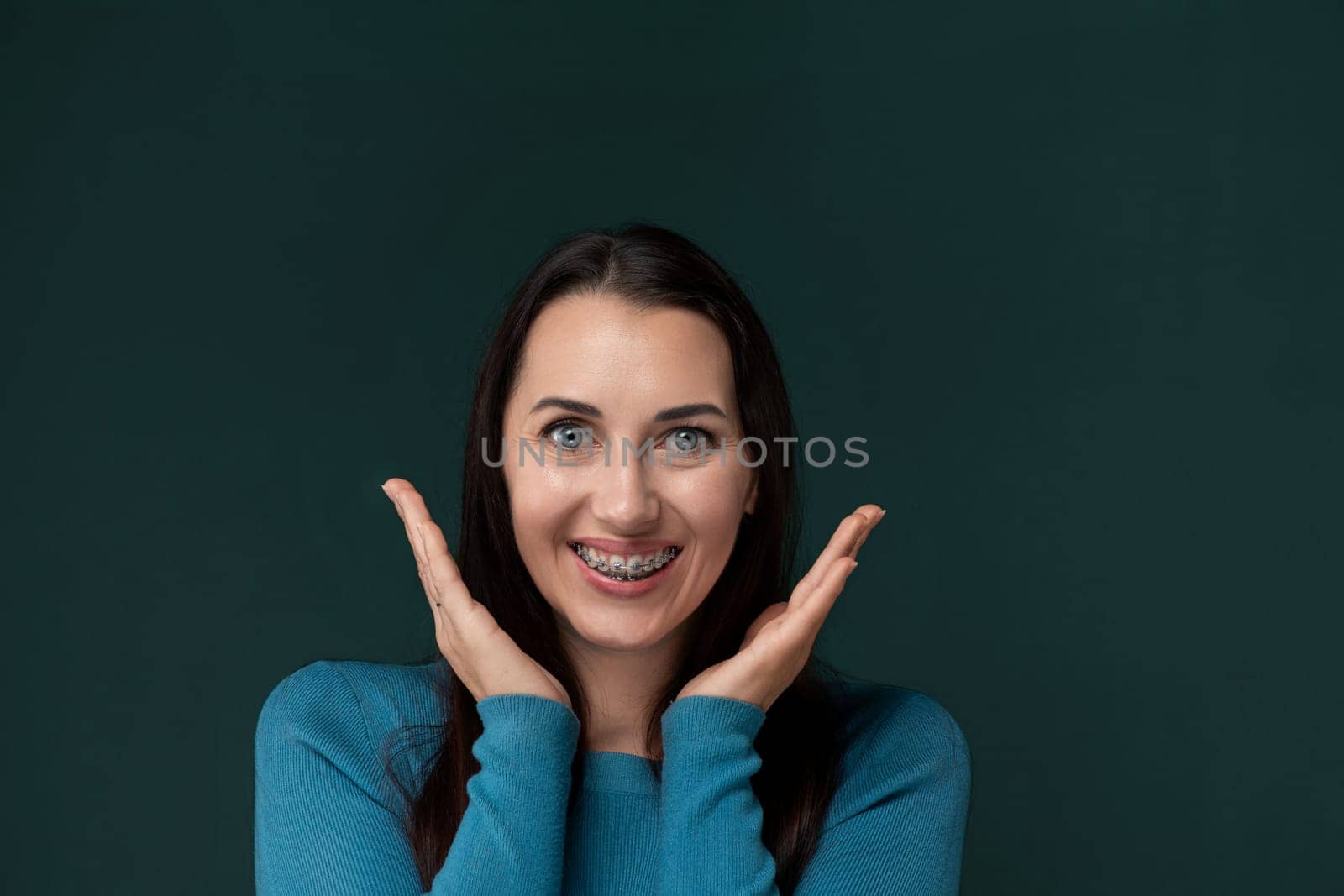 A woman is seen in the image, pulling a funny face while using her hands to distort her features. Her expression is playful and exaggerated, creating a humorous moment captured in the photograph.
