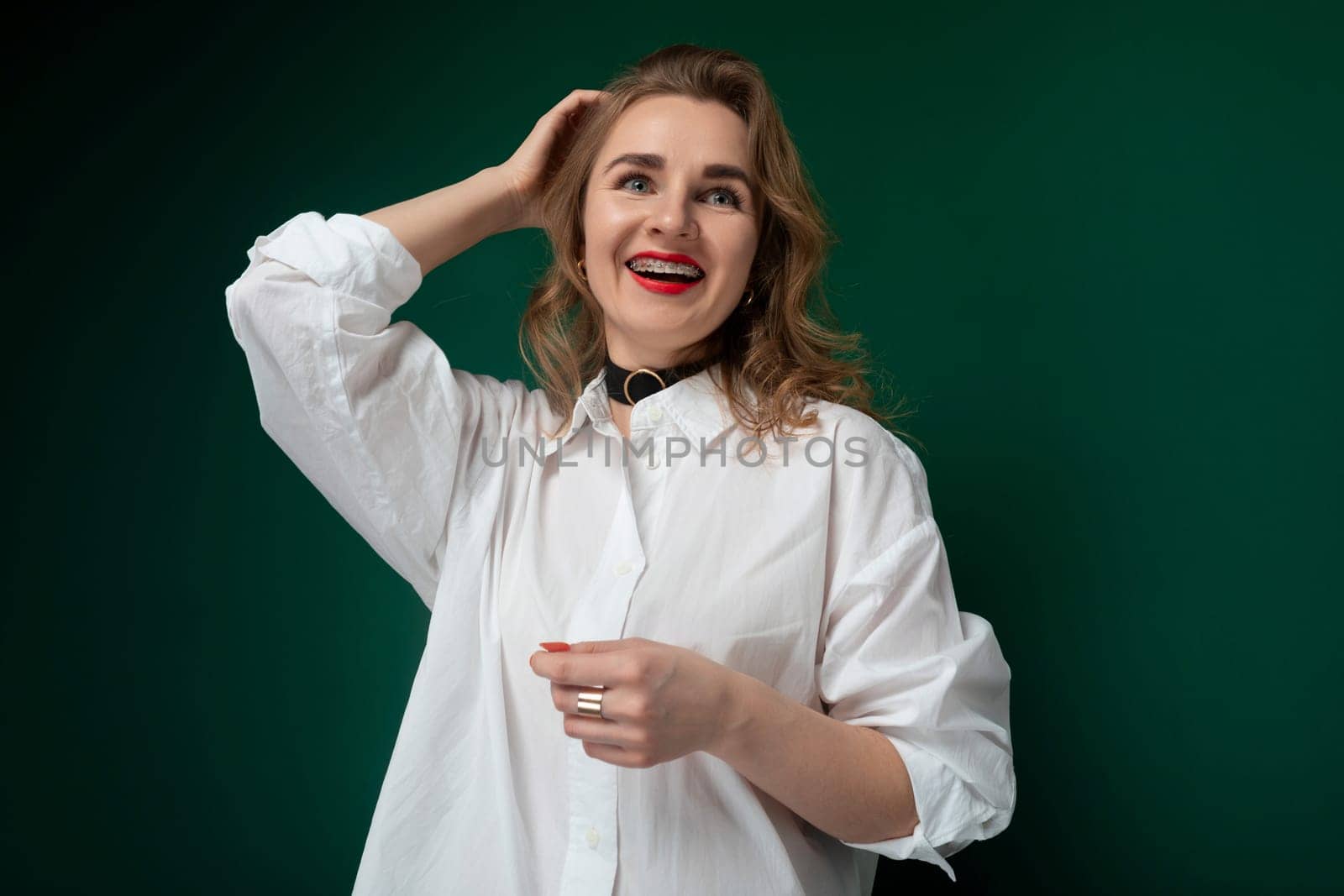 A woman wearing a white shirt is standing and striking a pose for a photograph. She looks directly at the camera with a confident expression, showcasing her outfit and style.