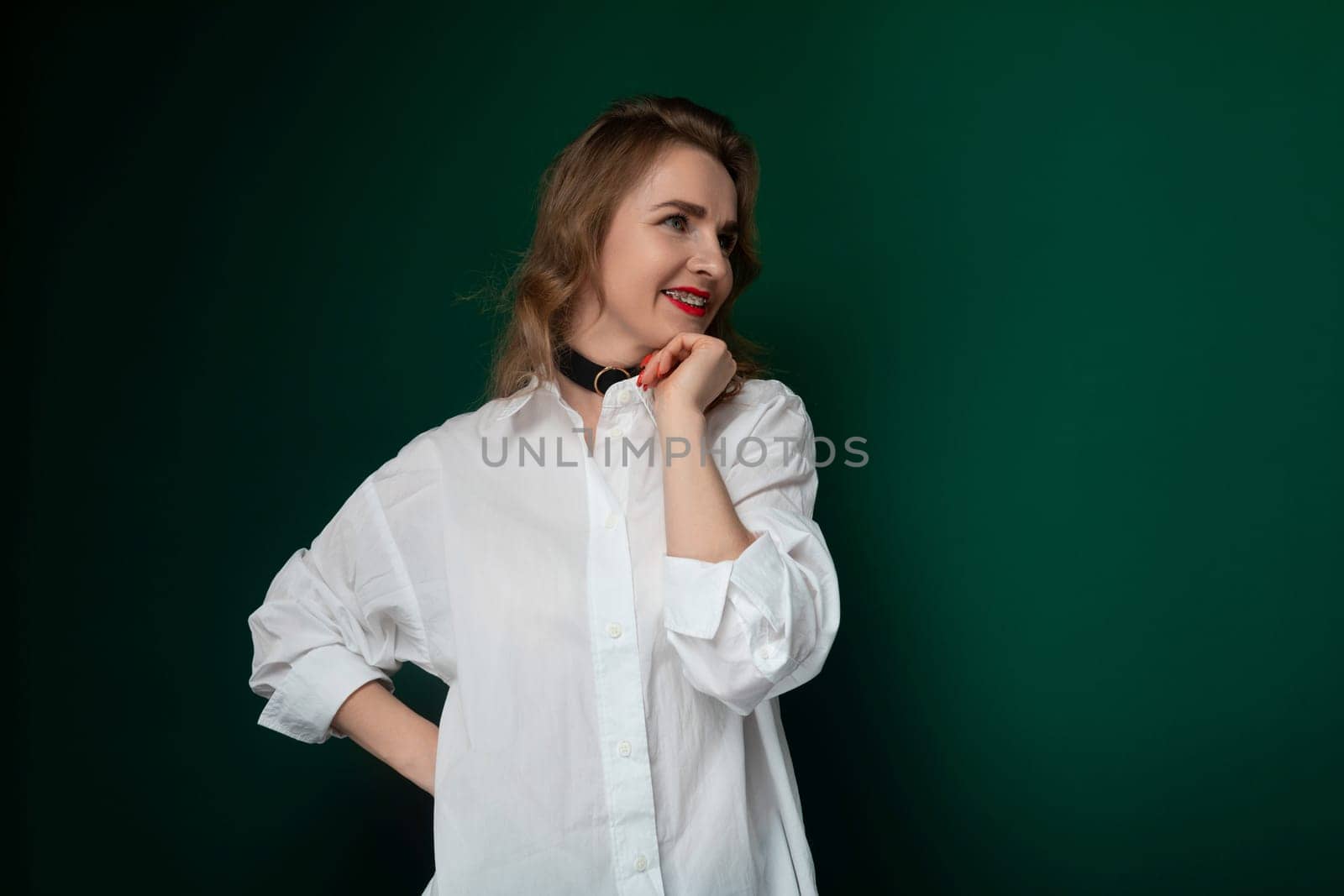 A woman wearing a white shirt is striking a pose for a photograph. She is standing confidently and smiling at the camera, showcasing her outfit and posture.