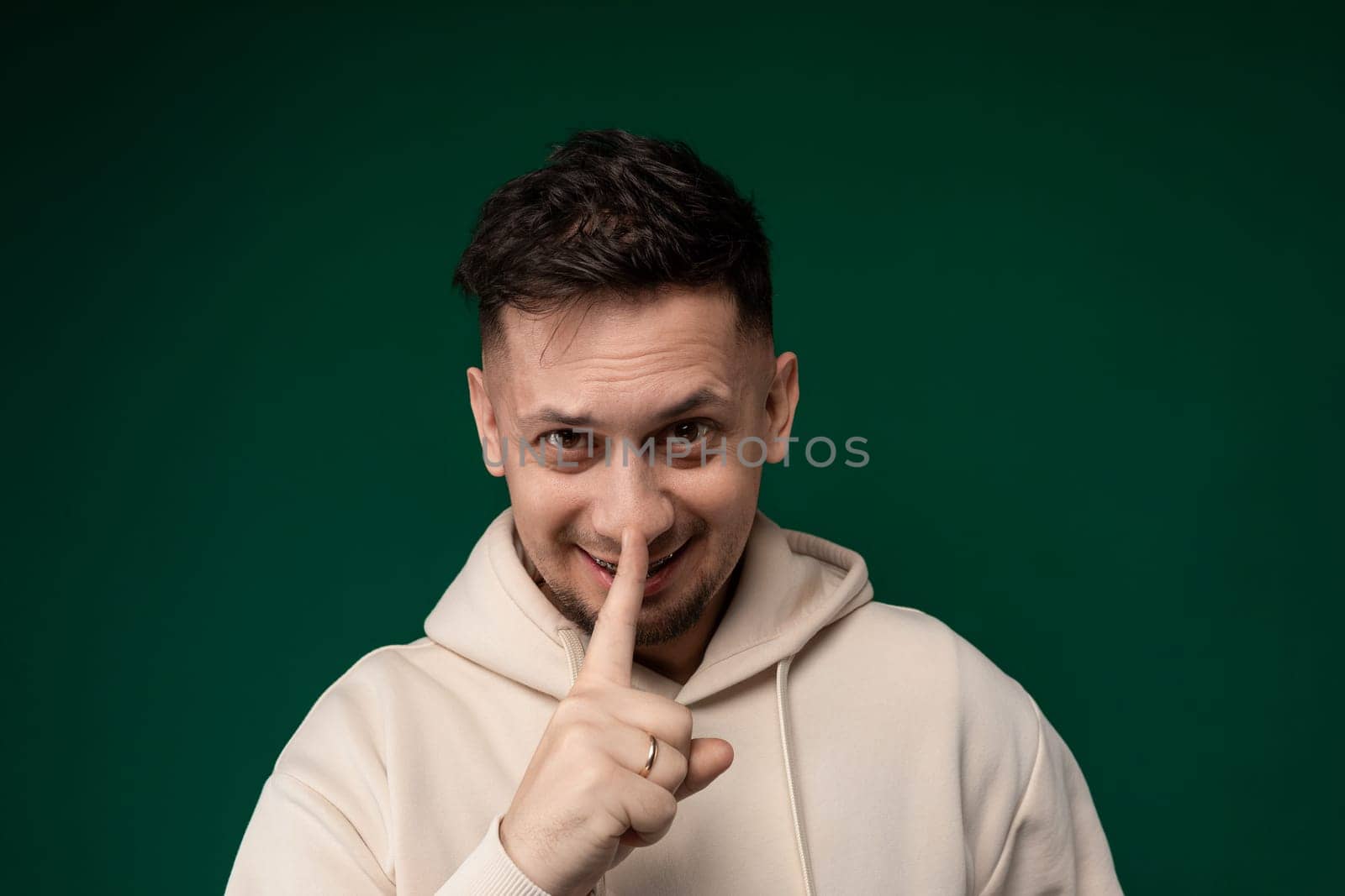 A man wearing a white hoodie is standing and making a finger sign with his hand, capturing a moment of gesture communication.