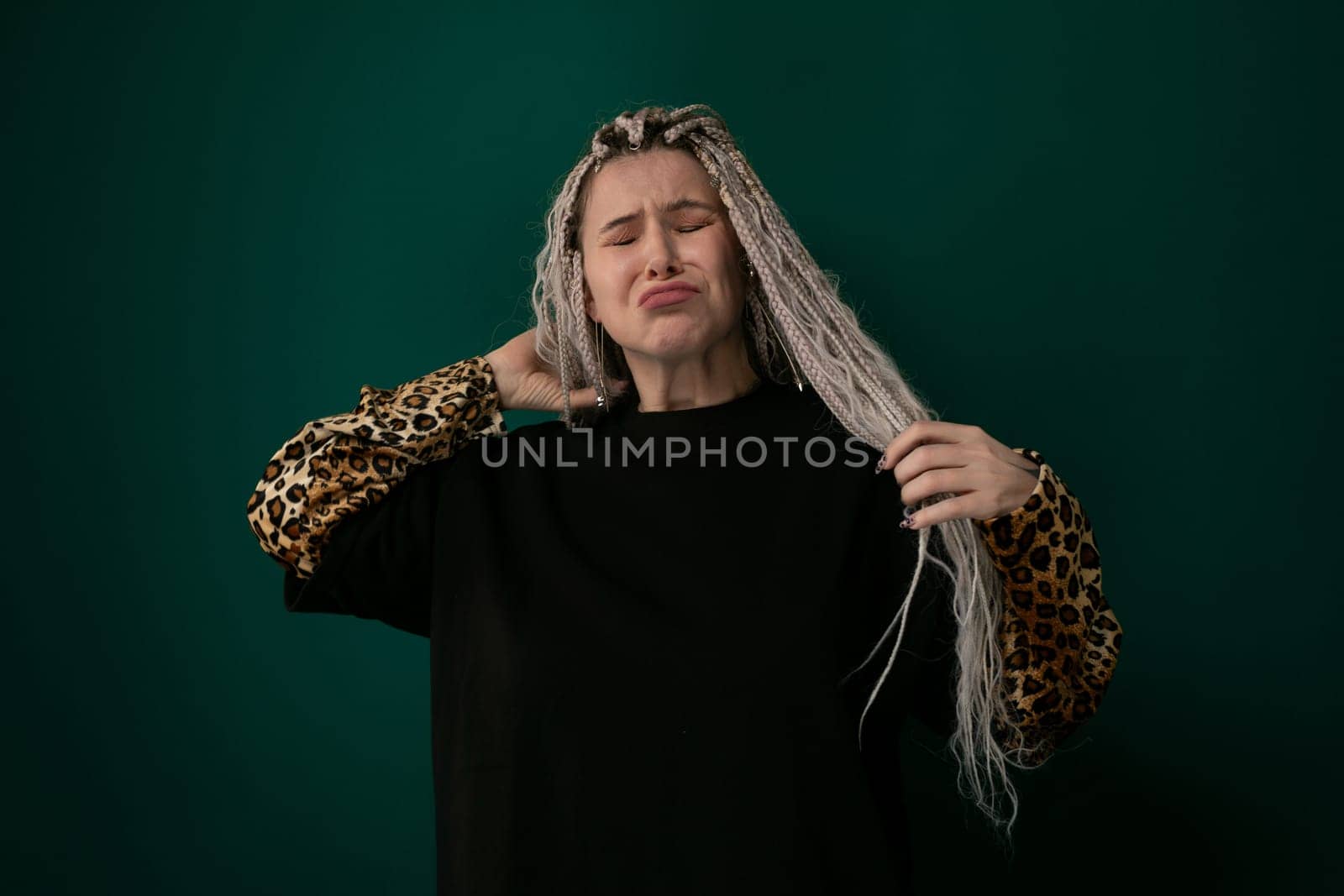 A woman with grey hair wearing a black shirt is standing against a neutral background. She appears composed and confident, looking directly at the camera. The womans grey hair contrasts with her black attire, creating a striking visual effect.