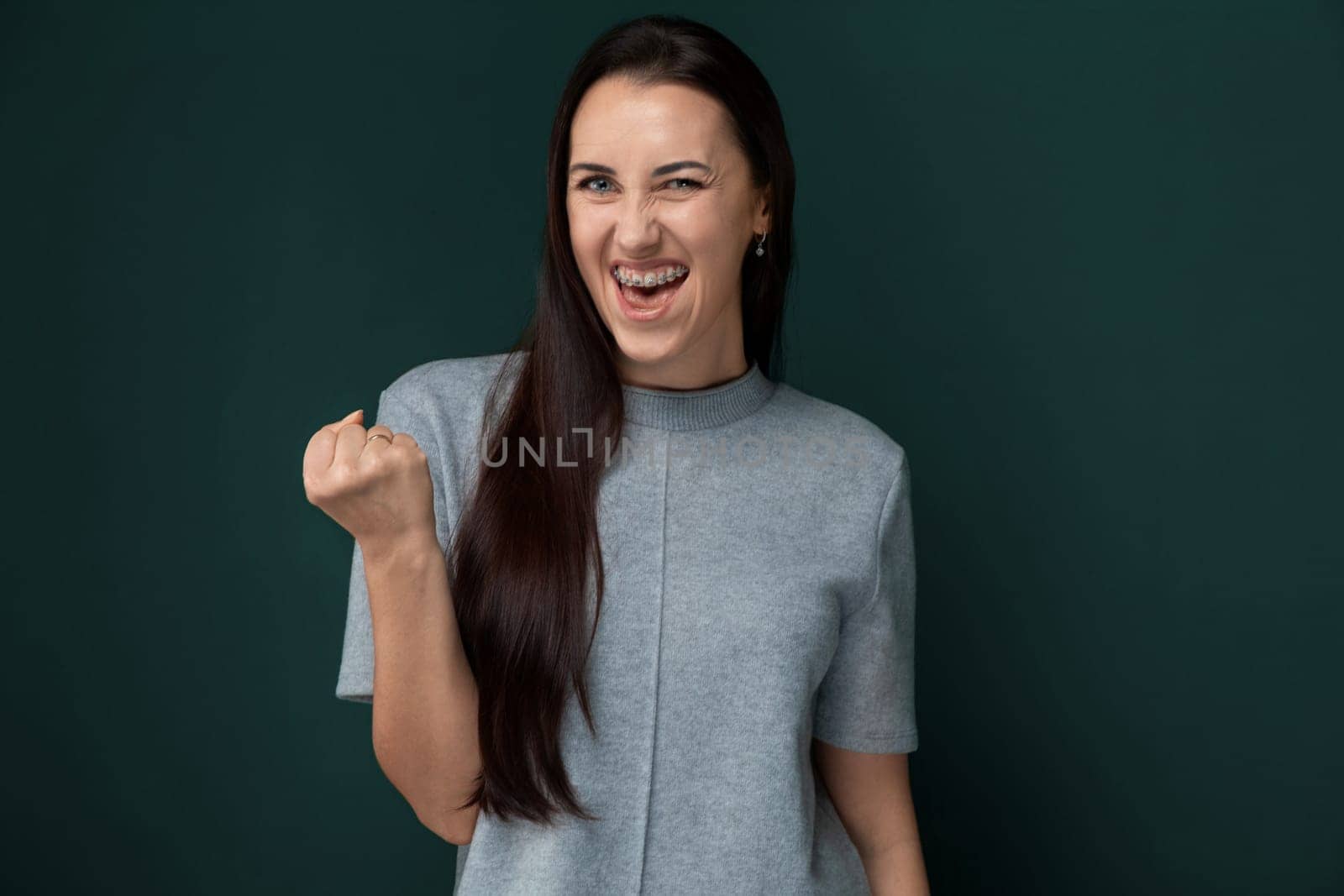 A woman with flowing long hair stands confidently in a gray shirt. Her hair cascades down her back as she strikes a pose.