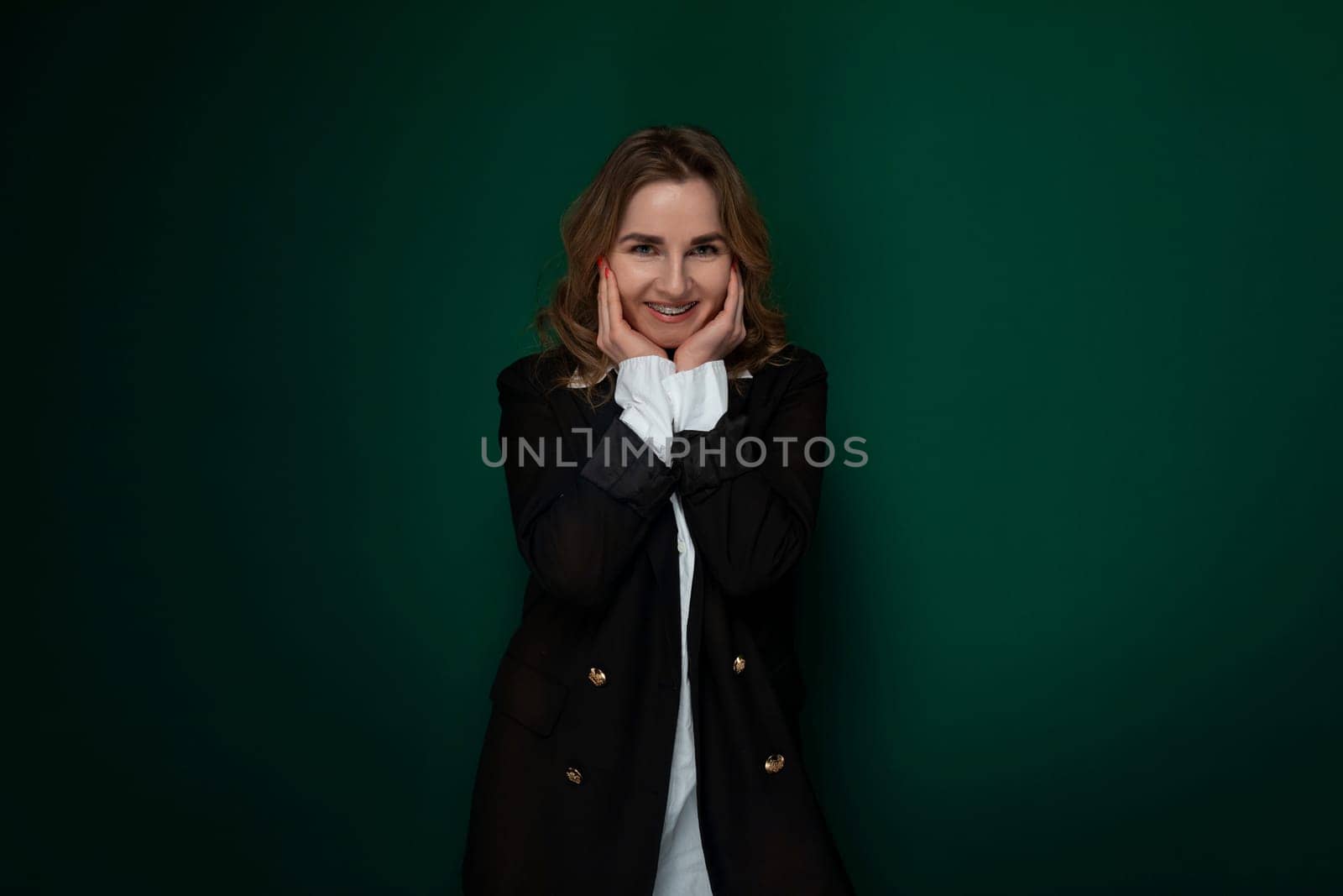 A woman is standing in a pose, with her hands covering her face as if framing it for a photograph. She appears confident and stylish as she strikes the pose for the camera. The background is simple, allowing her to be the main focus of the shot.