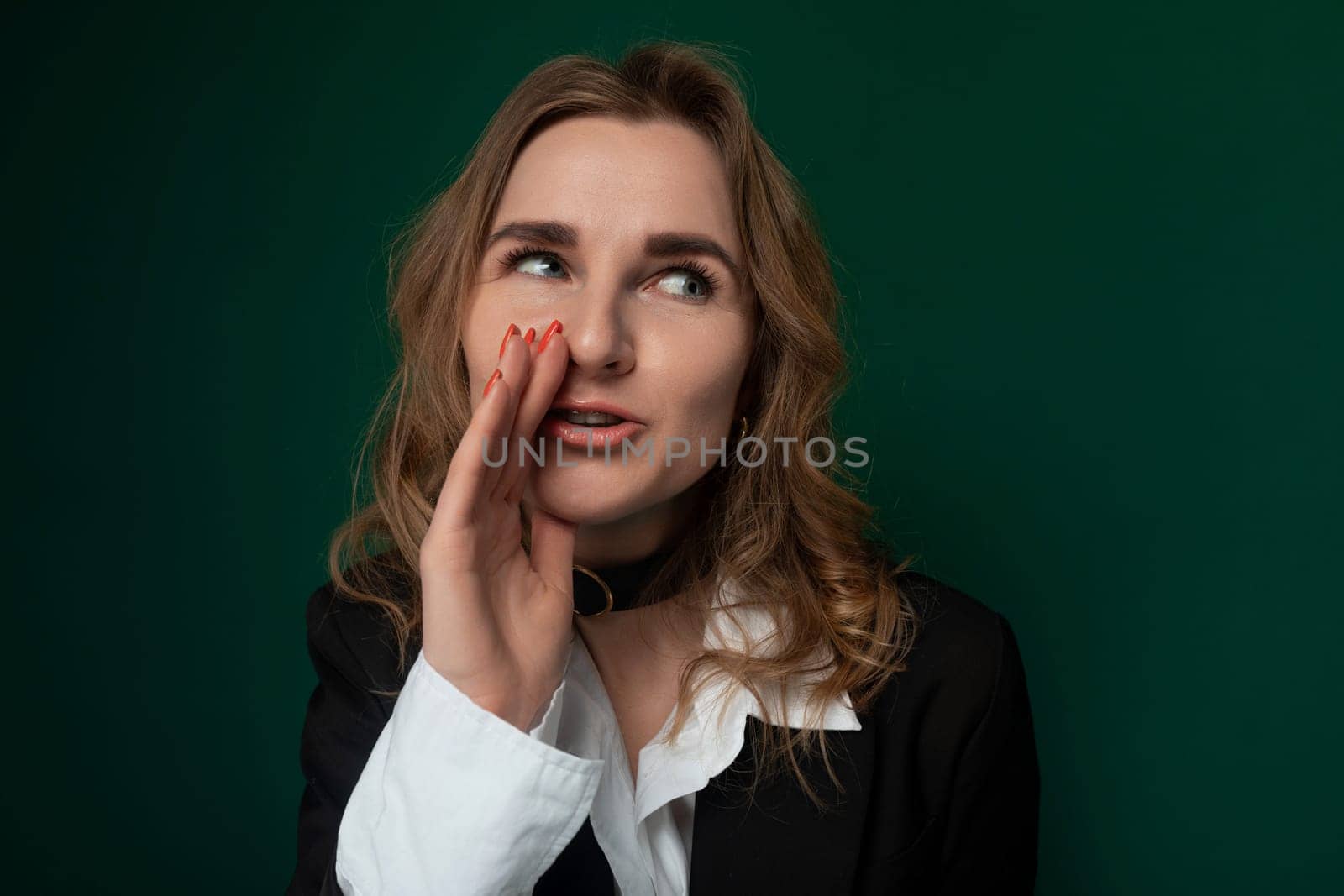 A woman stands with a surprised expression on her face, her eyes widened and mouth slightly open. She appears shocked or astonished by something she has just seen or heard.