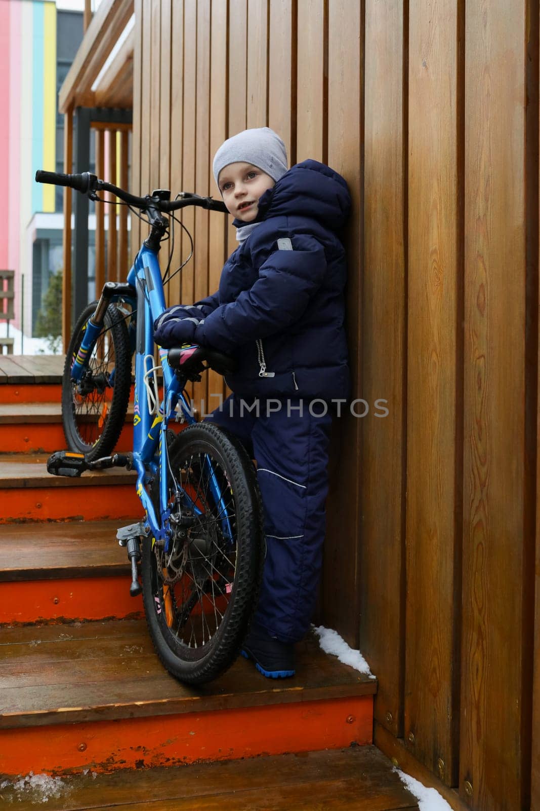 Child boy took a bike for a walk in winter.