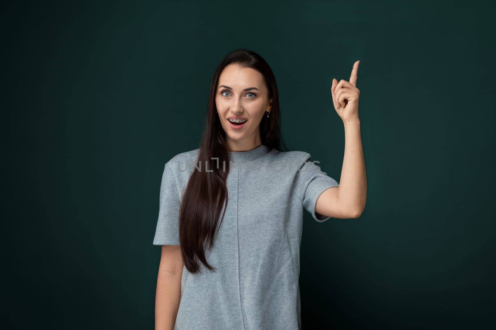 A woman is pointing at an object or direction with her finger, indicating something of interest. She is likely drawing attention to a specific item or location.