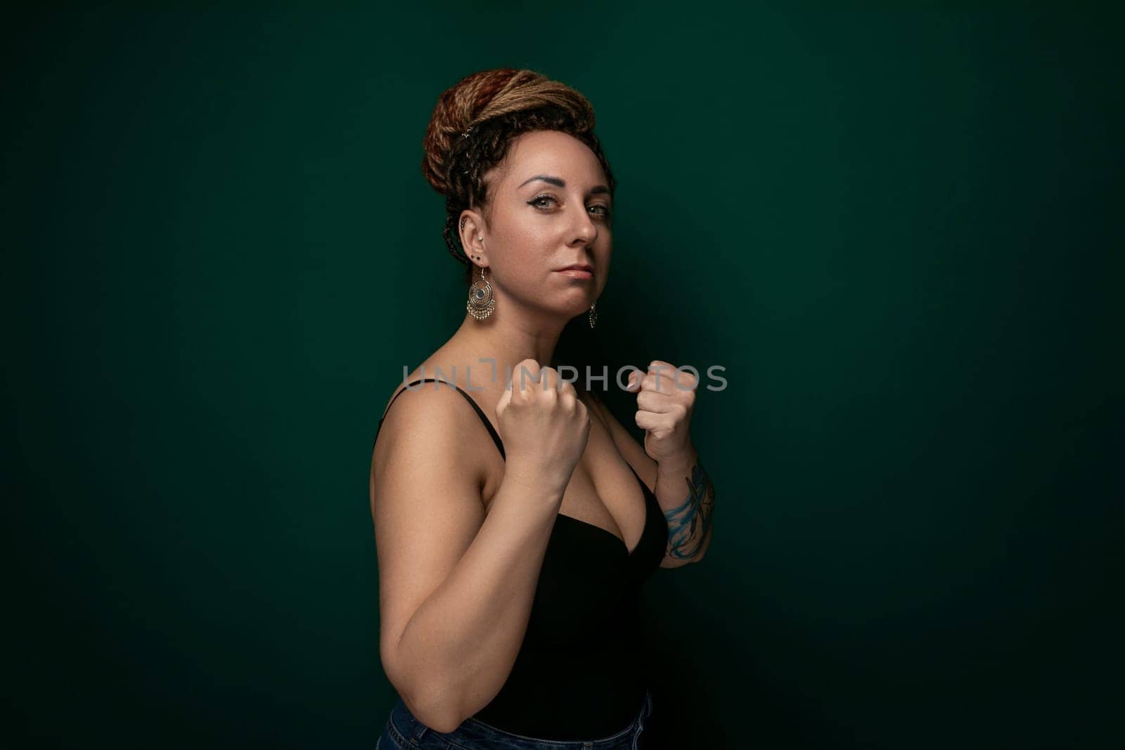 A woman in a black top confidently strikes a pose while someone takes her picture. Her posture exudes self-assurance, and she looks directly at the camera with a subtle smile.
