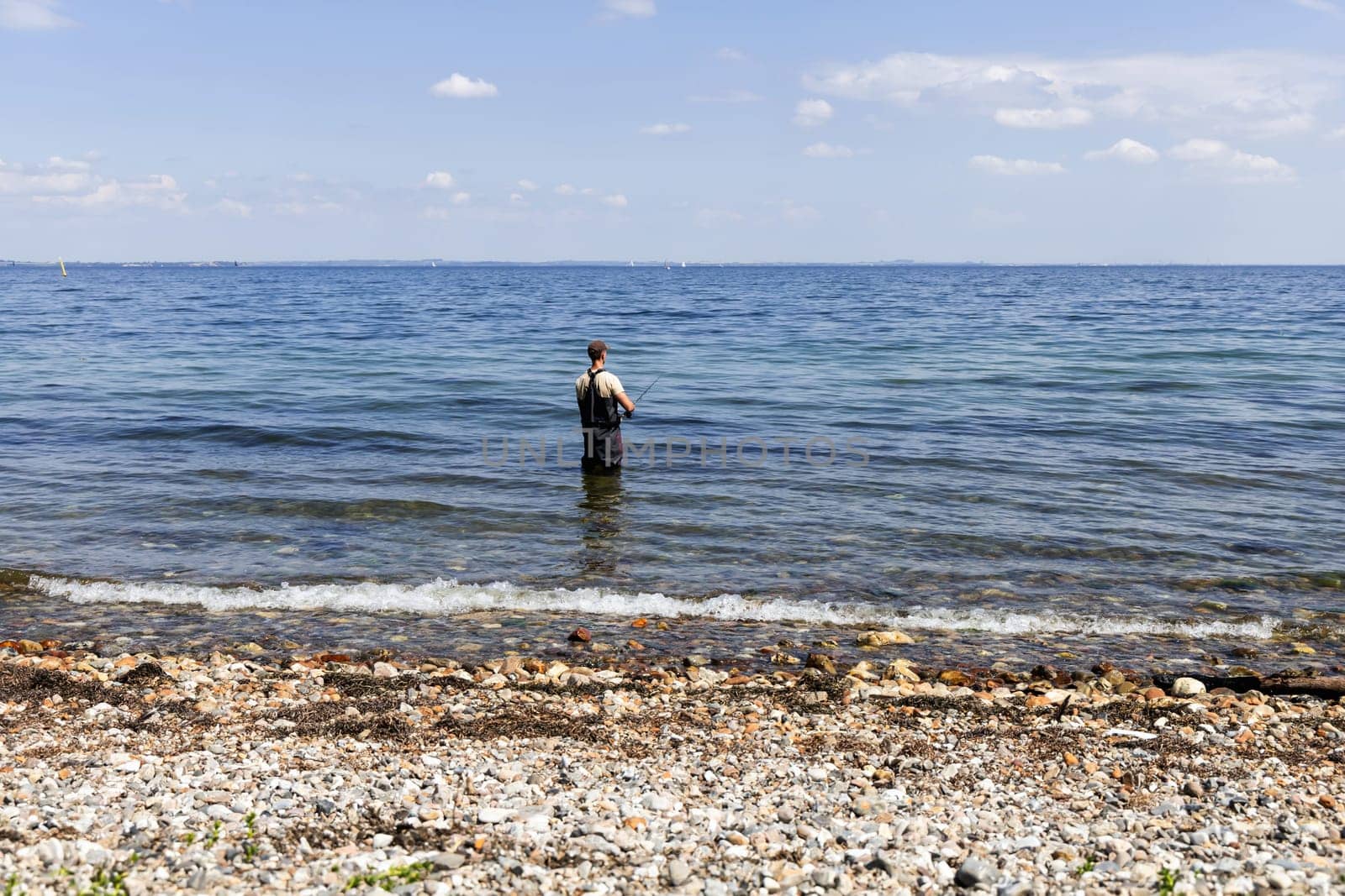 Fisherman catches fish with a fishing rod on the seashore. Beautiful seascape.