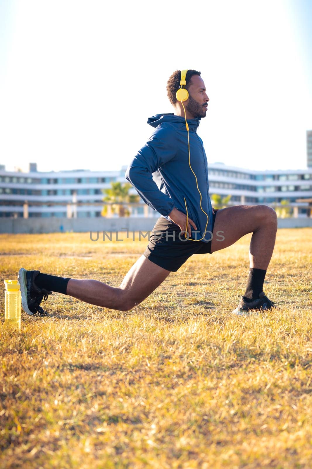 Active and fit male runner in leg warm-up stretch for running or cardio.Vertical by mariaphoto3