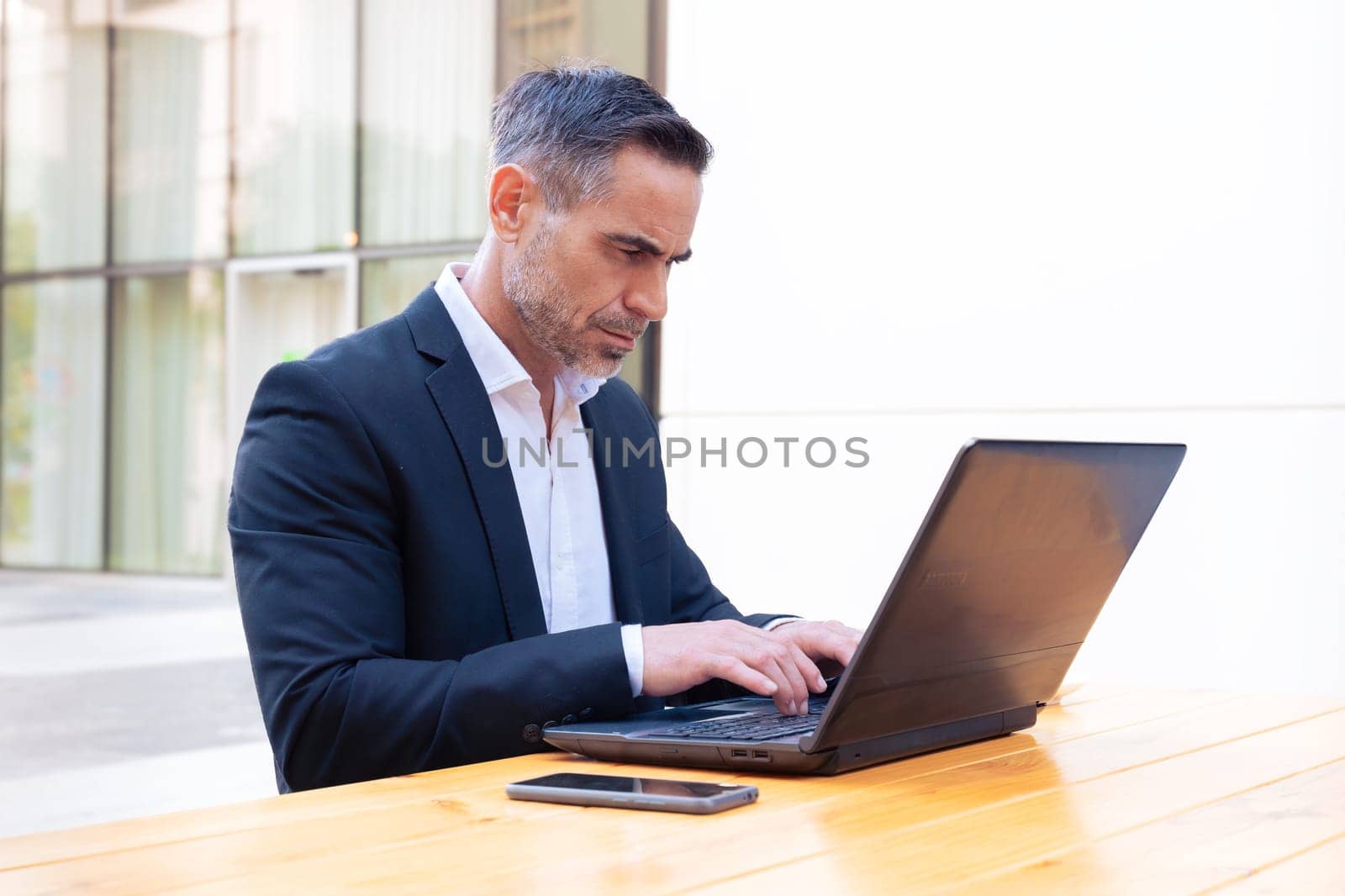 Business on the move: Businessman working on his laptop on the street. Man Hands Type On His Laptop Outdoors