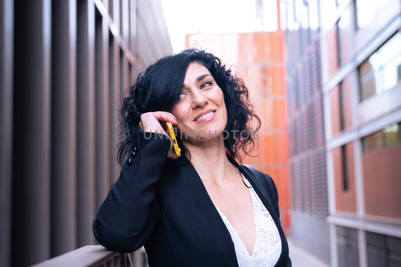 Beautiful middle-aged caucasian woman having a conversation on cell phone outdoors.