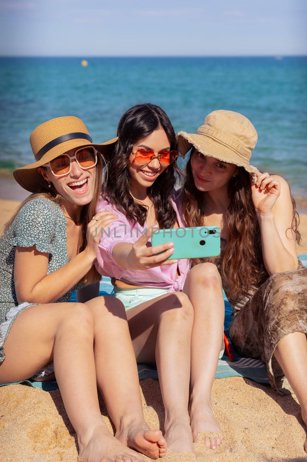 Group of smiling multiethnic women enjoying vacation. Beautiful and cheerful girls of generation z pose for a photo with a mobile phone.