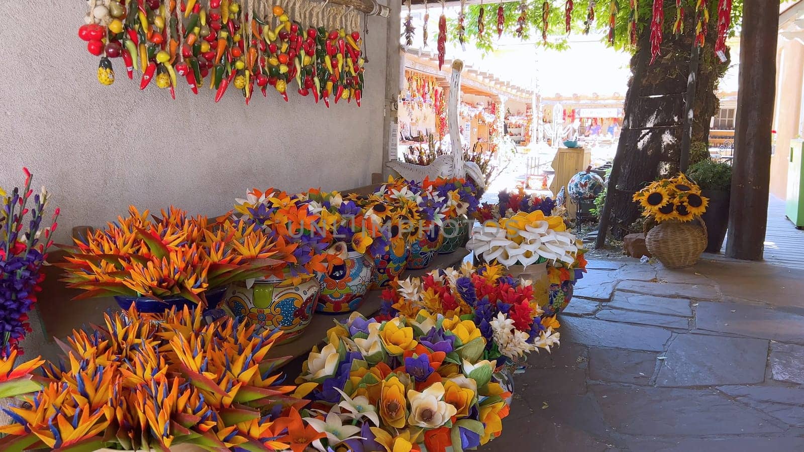 Santa Fe, New Mexico, USA-June 11, 2024-Slow motion-A vibrant outdoor market showcasing an array of colorful ceramics, pottery, and handcrafted items. Shoppers explore the unique local crafts under a sunny sky, surrounded by traditional adobe architecture.