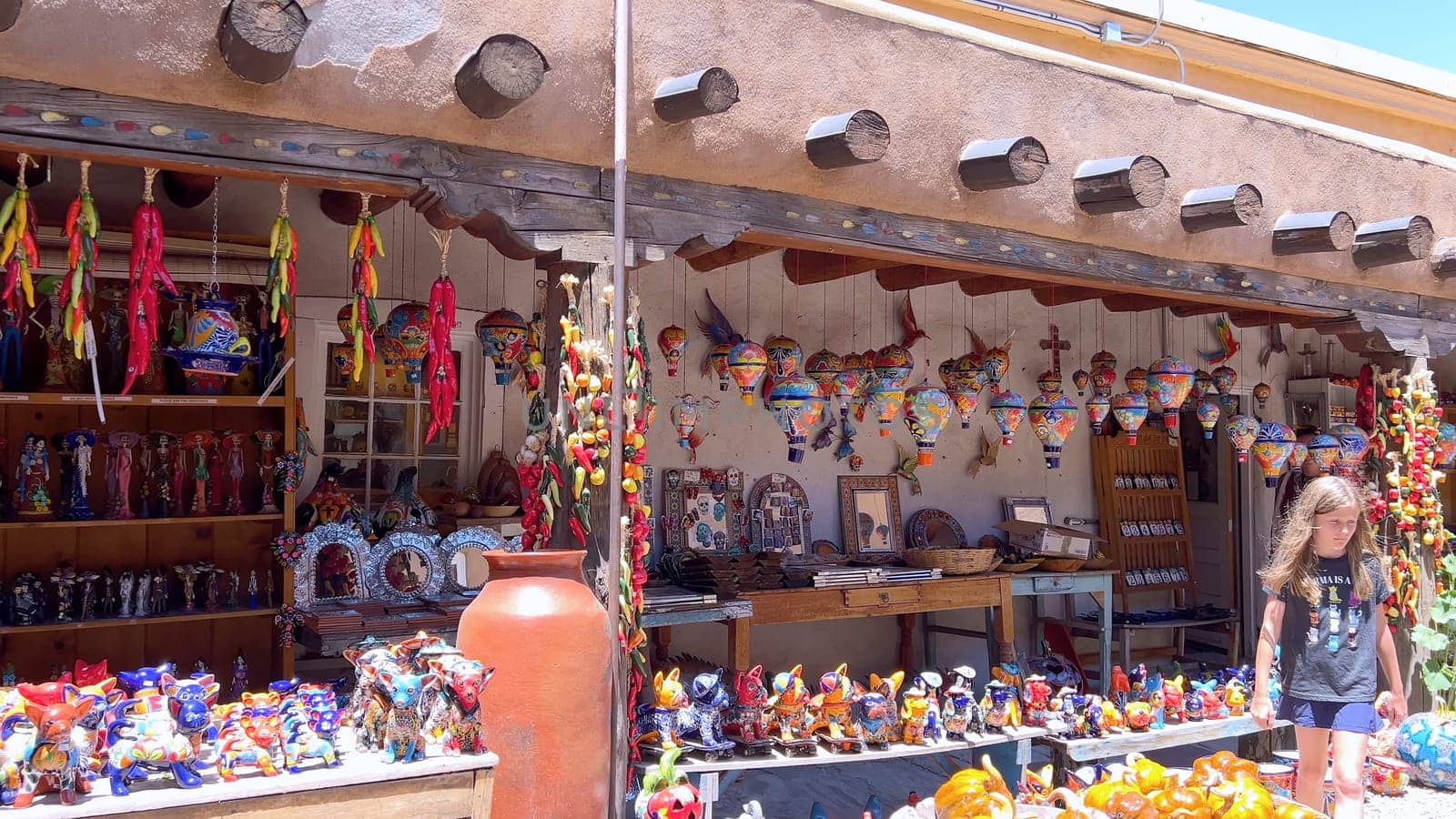 Santa Fe, New Mexico, USA-June 11, 2024-Slow motion-A vibrant outdoor market showcasing an array of colorful ceramics, pottery, and handcrafted items. Shoppers explore the unique local crafts under a sunny sky, surrounded by traditional adobe architecture.