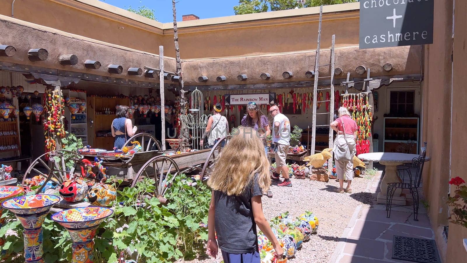 Santa Fe, New Mexico, USA-June 11, 2024-Slow motion-A vibrant outdoor market showcasing an array of colorful ceramics, pottery, and handcrafted items. Shoppers explore the unique local crafts under a sunny sky, surrounded by traditional adobe architecture.