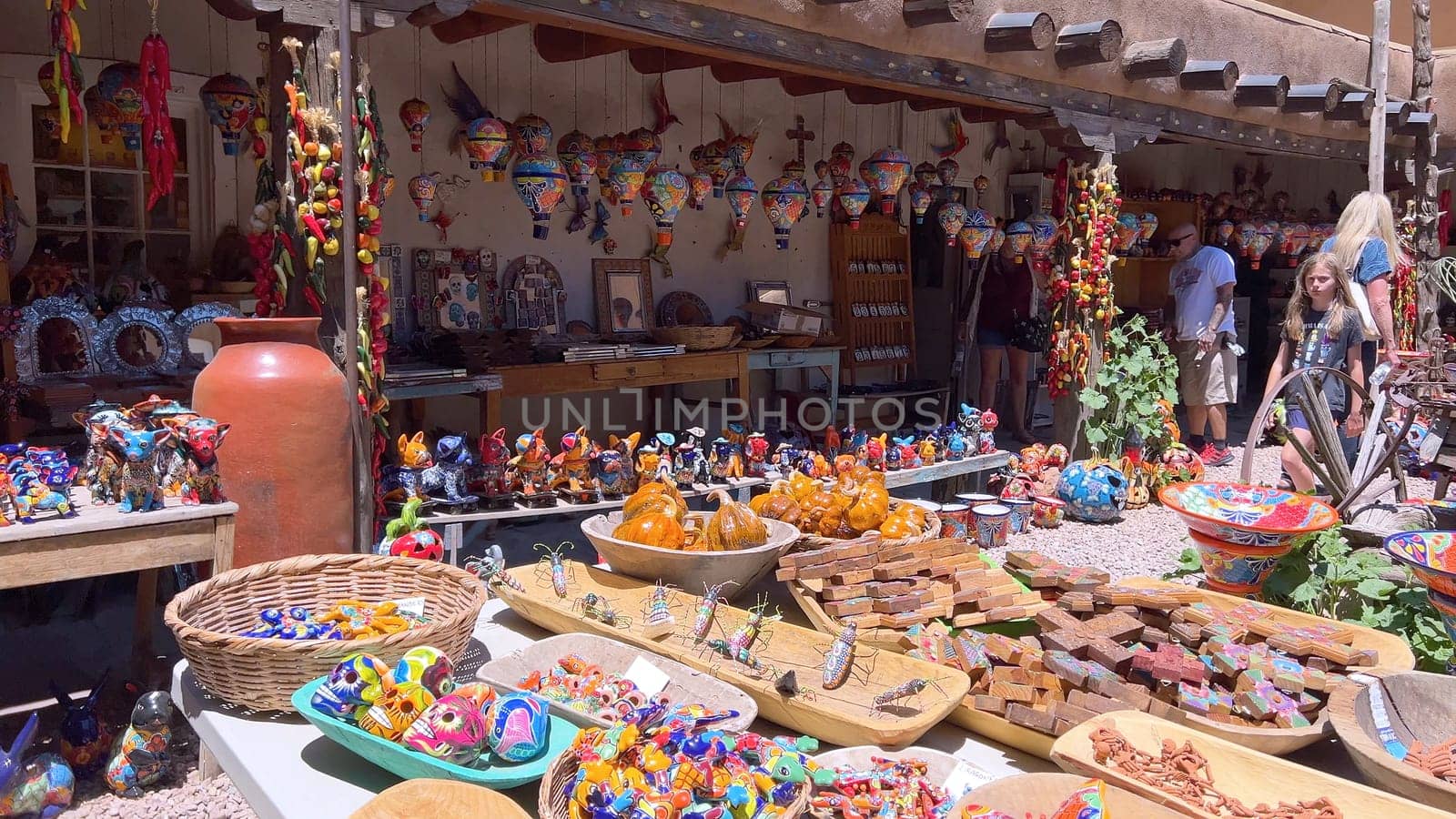 Santa Fe, New Mexico, USA-June 11, 2024-Slow motion-A vibrant outdoor market showcasing an array of colorful ceramics, pottery, and handcrafted items. Shoppers explore the unique local crafts under a sunny sky, surrounded by traditional adobe architecture.