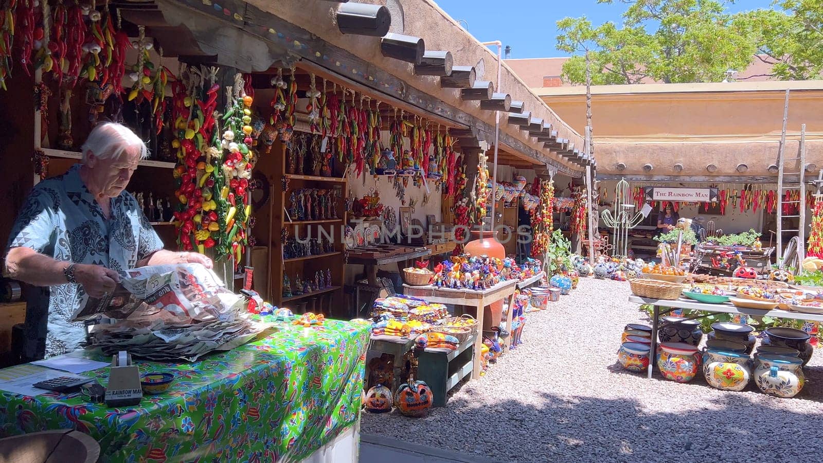 Santa Fe, New Mexico, USA-June 11, 2024-Slow motion-A vibrant outdoor market showcasing an array of colorful ceramics, pottery, and handcrafted items. Shoppers explore the unique local crafts under a sunny sky, surrounded by traditional adobe architecture.