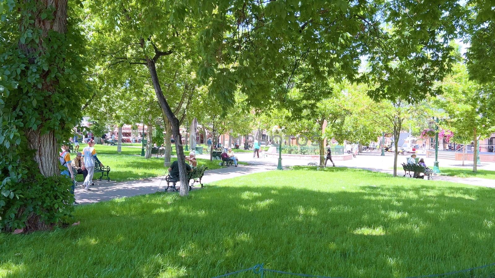 Santa Fe, New Mexico, USA-June 11, 2024-Slow motion-The main square of a historic downtown area featuring traditional adobe buildings, lively shops, and pedestrians enjoying a sunny day.