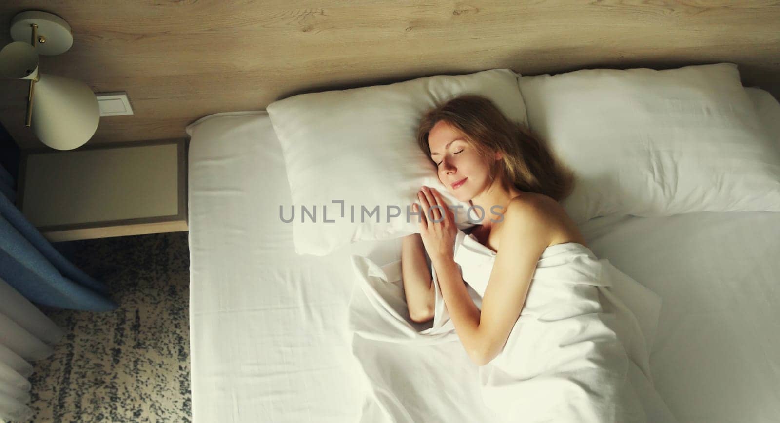 Young woman sleeping lying in bed on white soft comfortable pillow in bedroom at home
