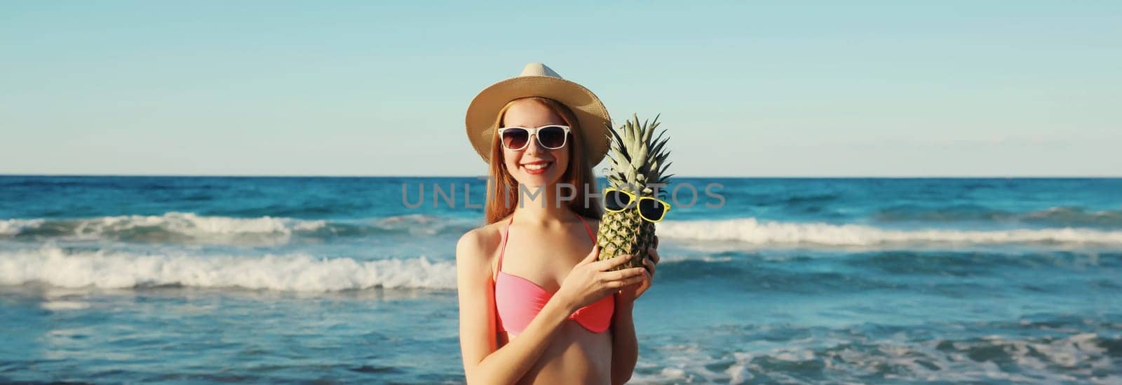 Summer vacation, beautiful happy woman in bikini swimsuit, hat, pineapple fruits on the beach at sea by Rohappy