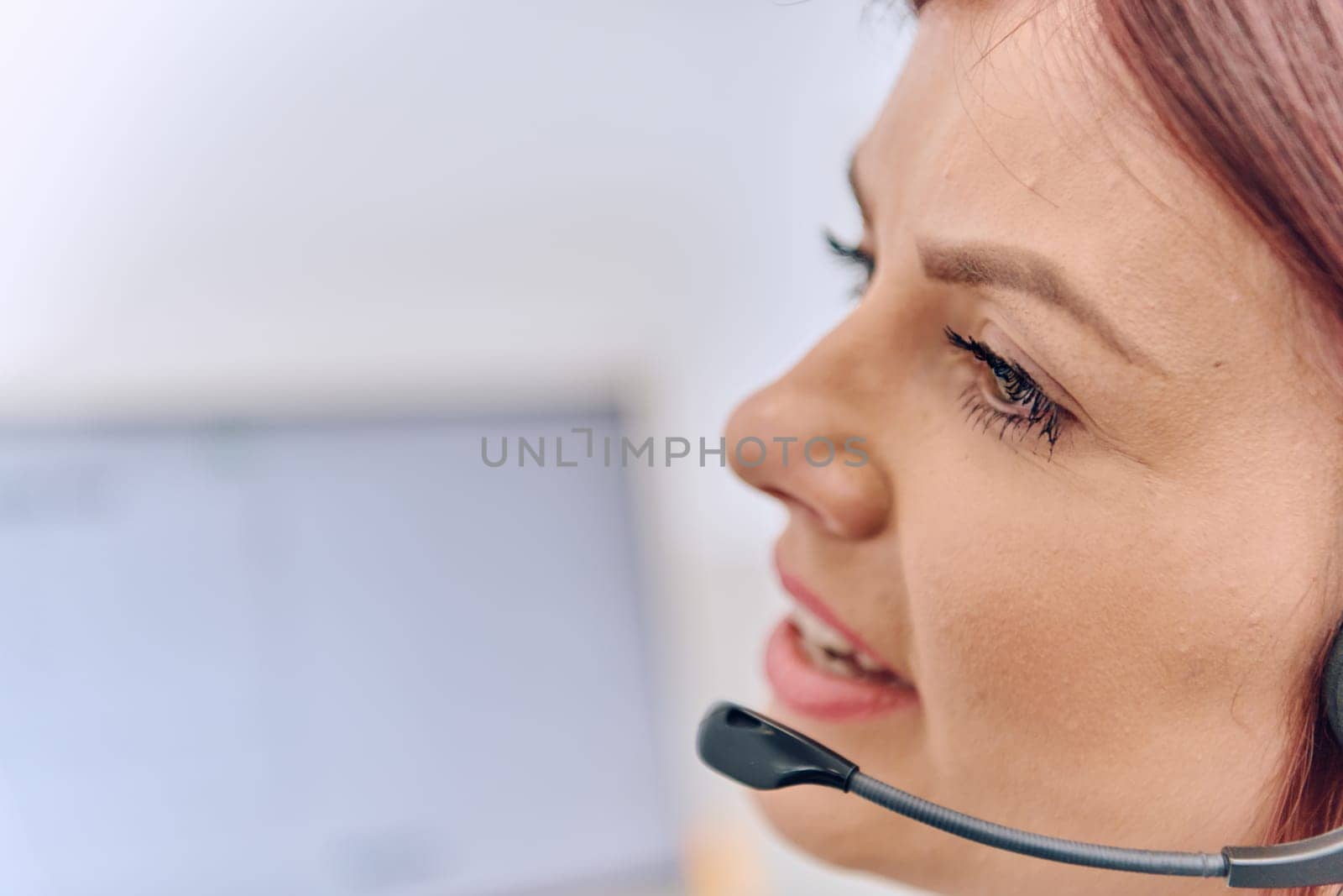 Friendly call center agent answering incoming calls with a headset, providing customer service remotely. Happy woman using her excellent communication skills to resolves customer issues.