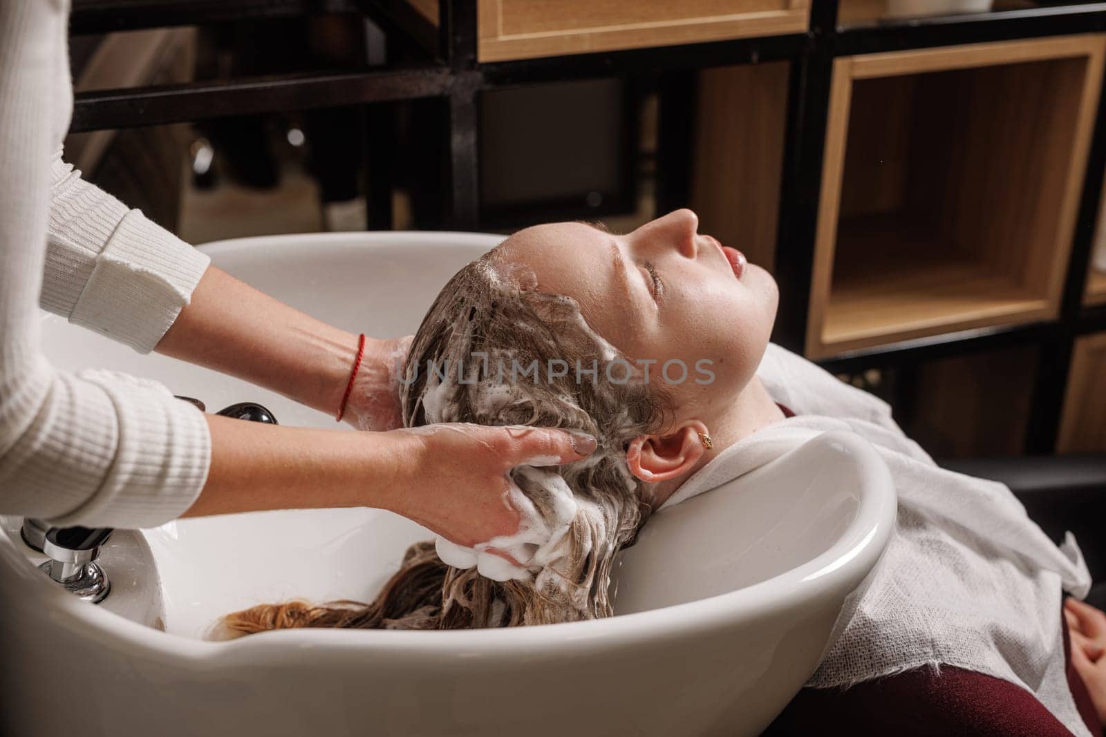 beauty salon master washes client's hair with shampoo for hair care in beauty salon, professional hairdresser,
