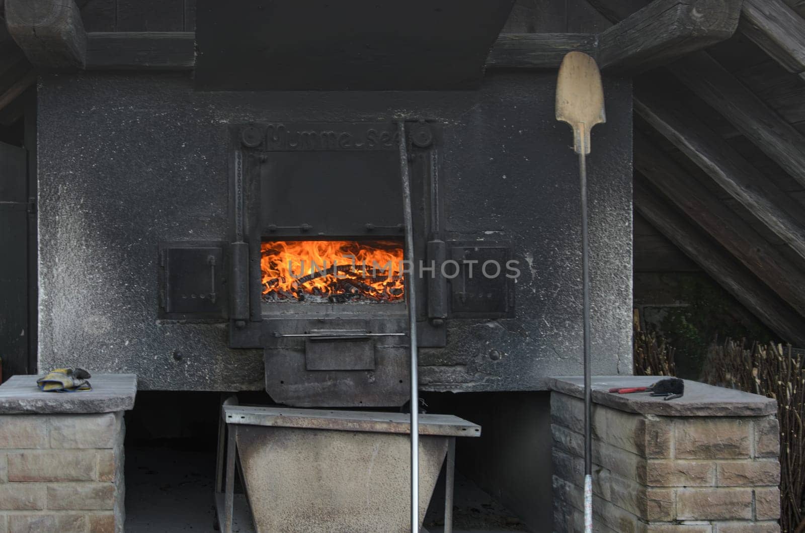 Rustic wood oven glowing with flames. Red fire in black oven.