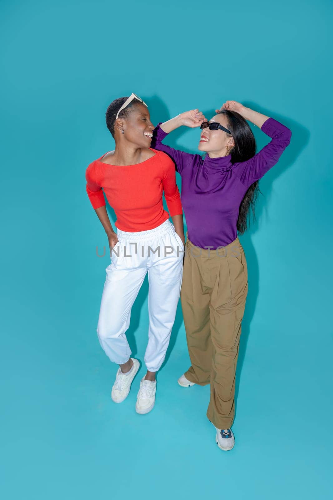 Two women pose on blue studio background. High quality photo