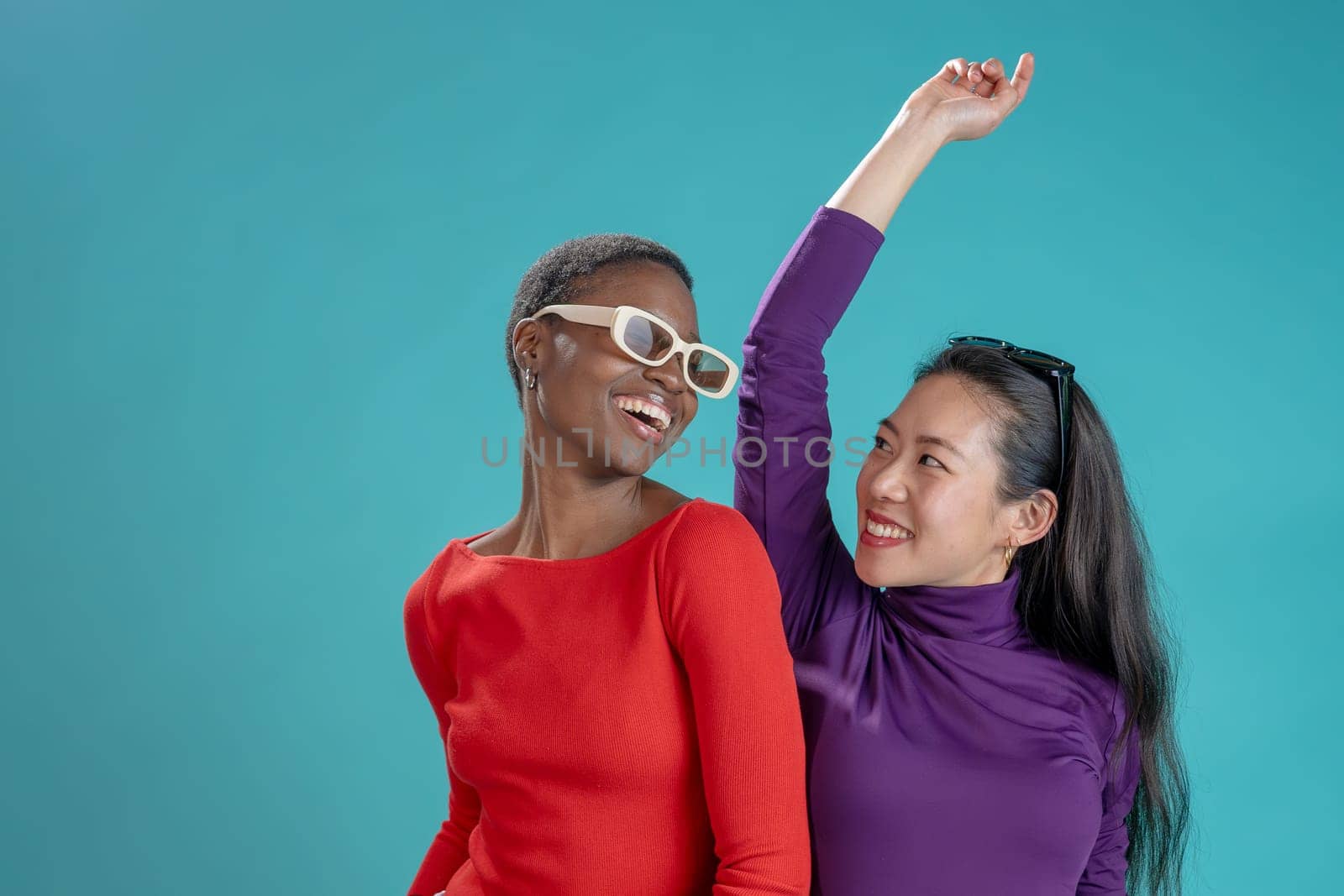 Two happy women pose on blue studio background by PaulCarr