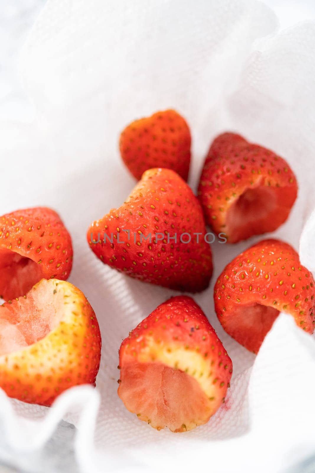 Freshly washed and dried strawberries are carefully arranged in a glass bowl lined with paper towel, ready for snacking or further use.