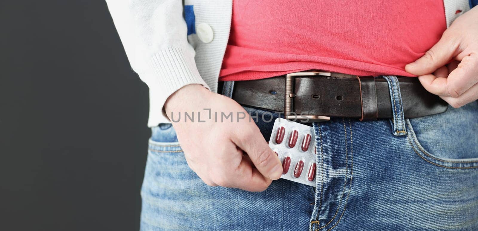 Man takes male pills out of fly of his pants. Erectile function problems concept