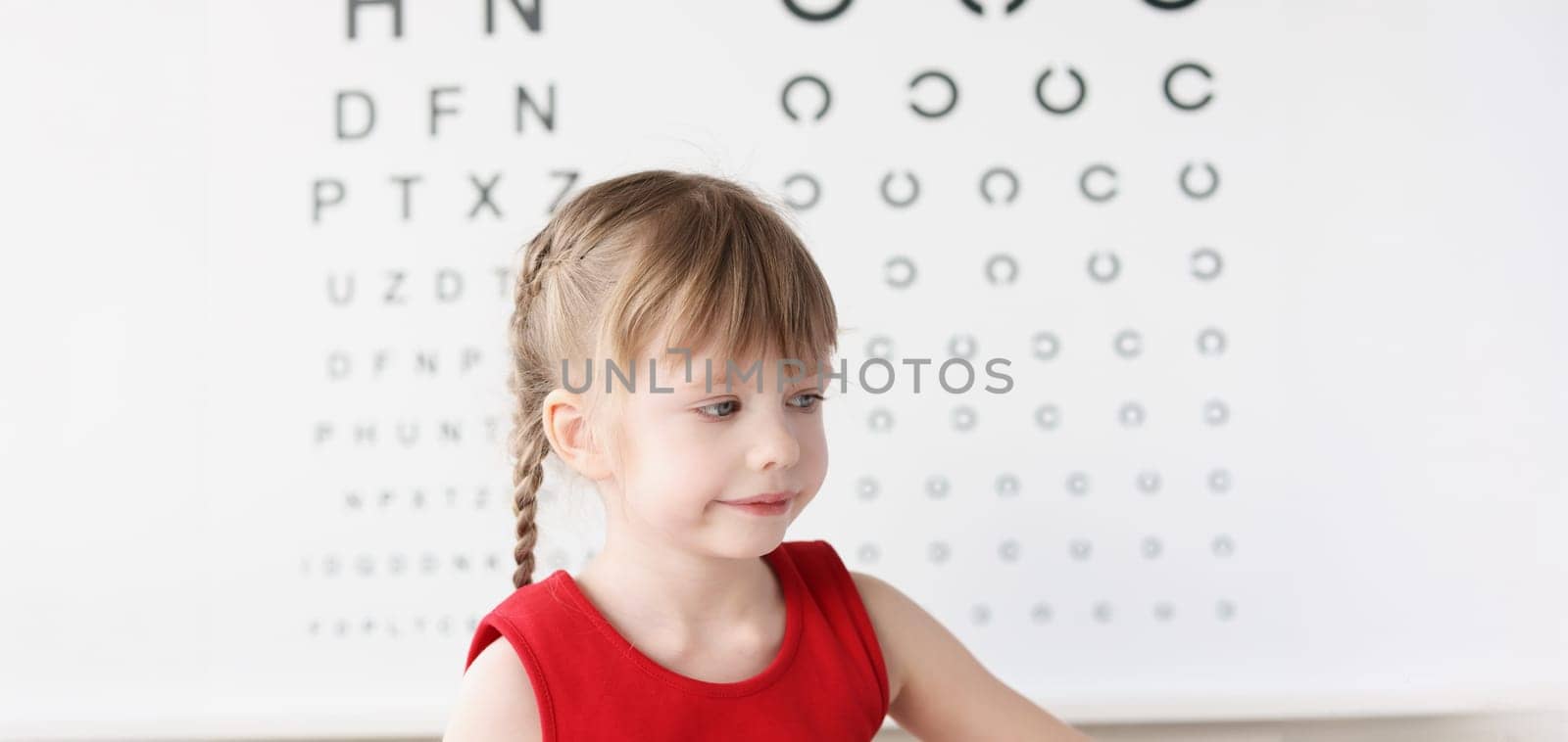 Little girl sitting near table for eye examination. Vision correction in children concept