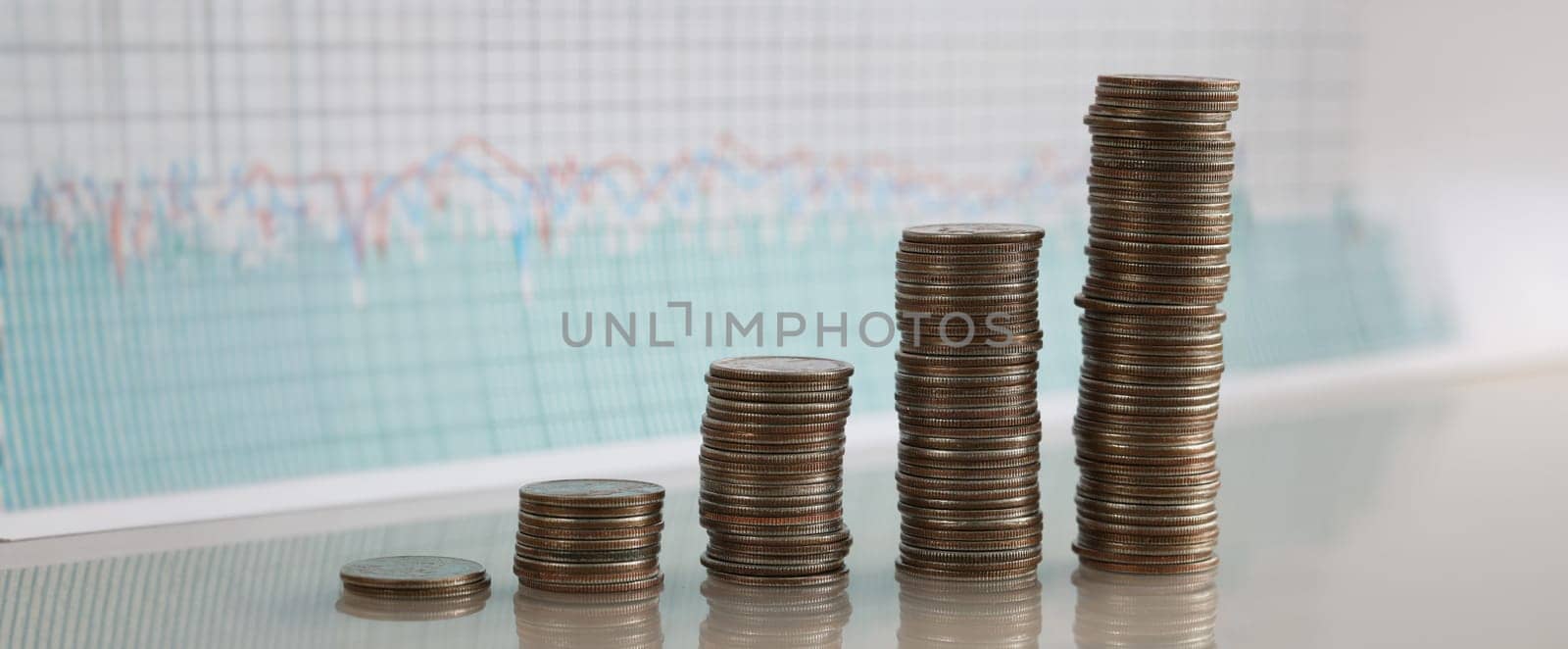 Stacks of coins increasing in row against background of financial indicators. Most profitable and most unprofitable investment projects concept