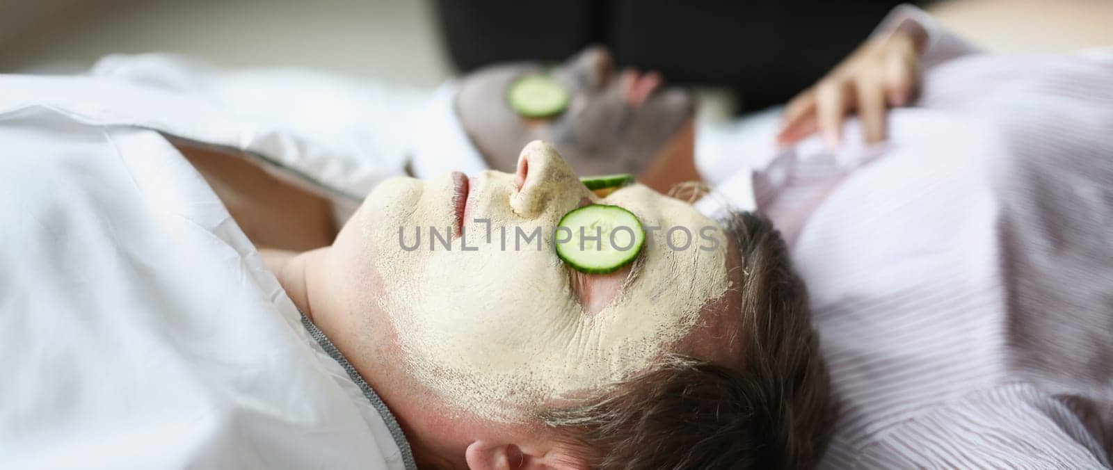 Man and woman applied clay rejuvenating mask to their faces by kuprevich