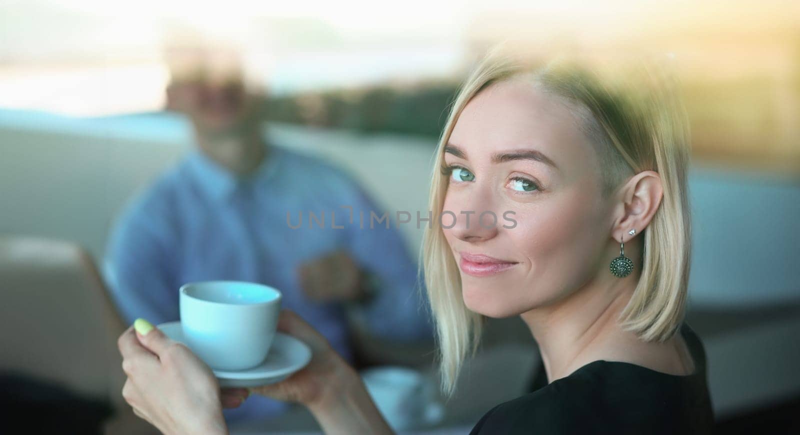 Portrait of smiling woman with cup at meeting in cafe. Date and business meeting concept