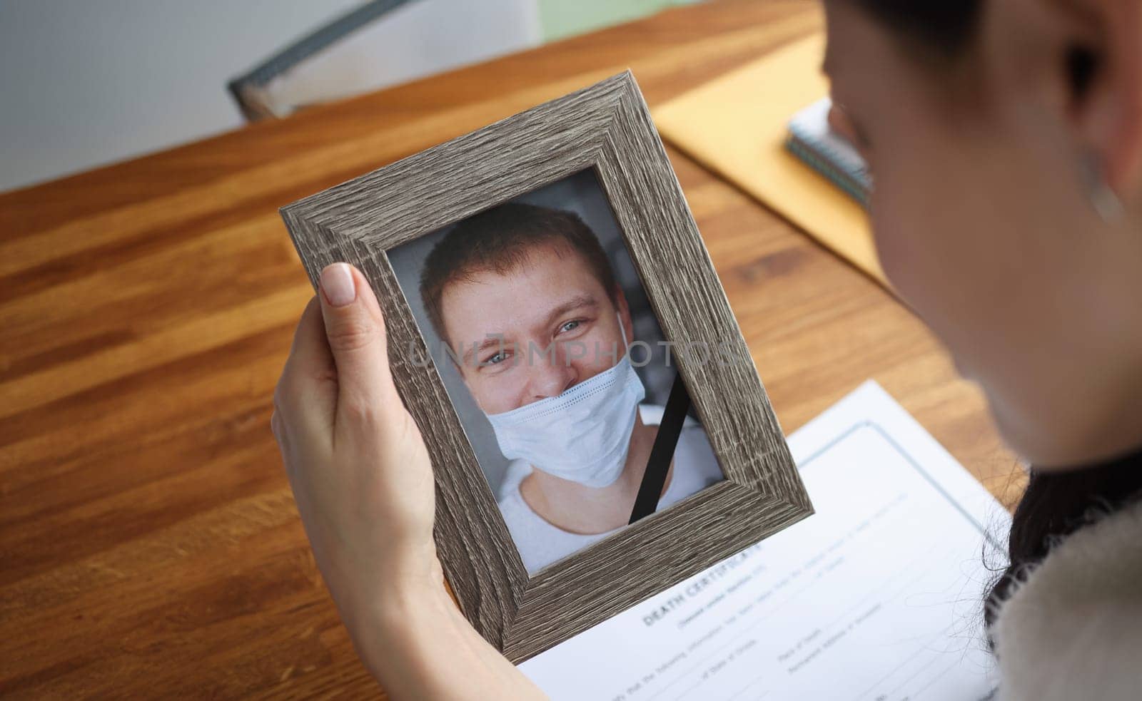 Woman crying over portrait of deceased young man closeup. How to properly wear medical protective face mask concept