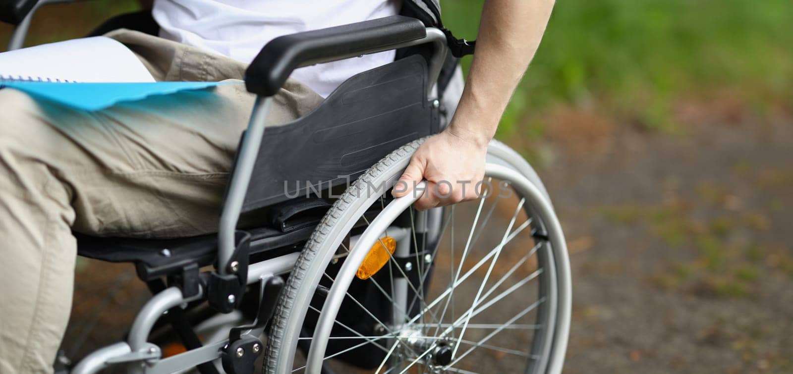 Man in wheelchair holds wheel with his hand. Rehabilitation of people with disabilities concept
