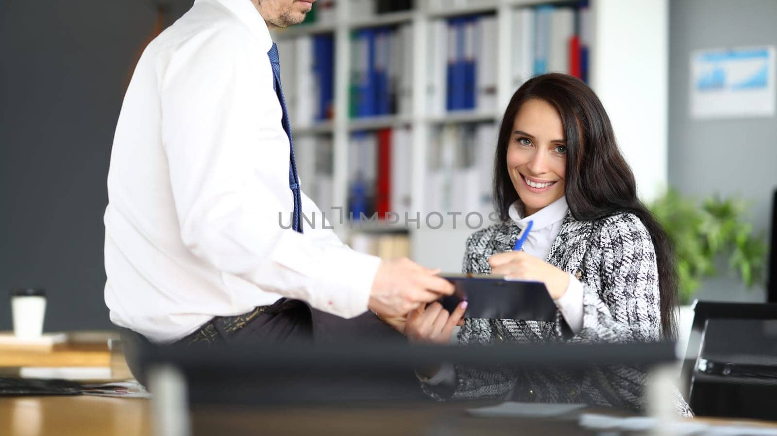 Smiling woman puts signature on documents. Conclusion of business deal concept