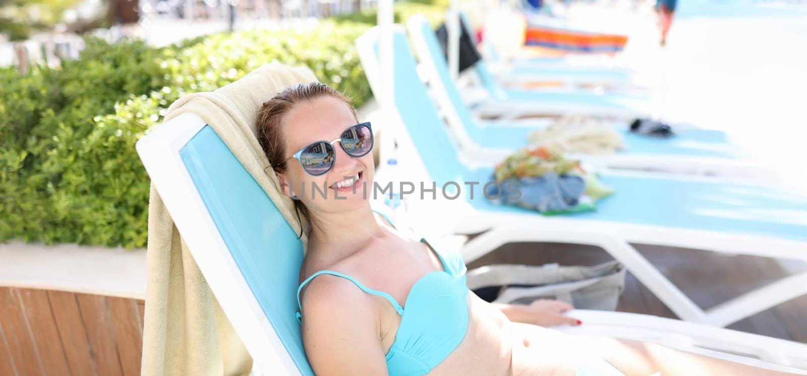 Smiling woman lies in sunglasses on sunbed. Relaxing vacation vacation concept