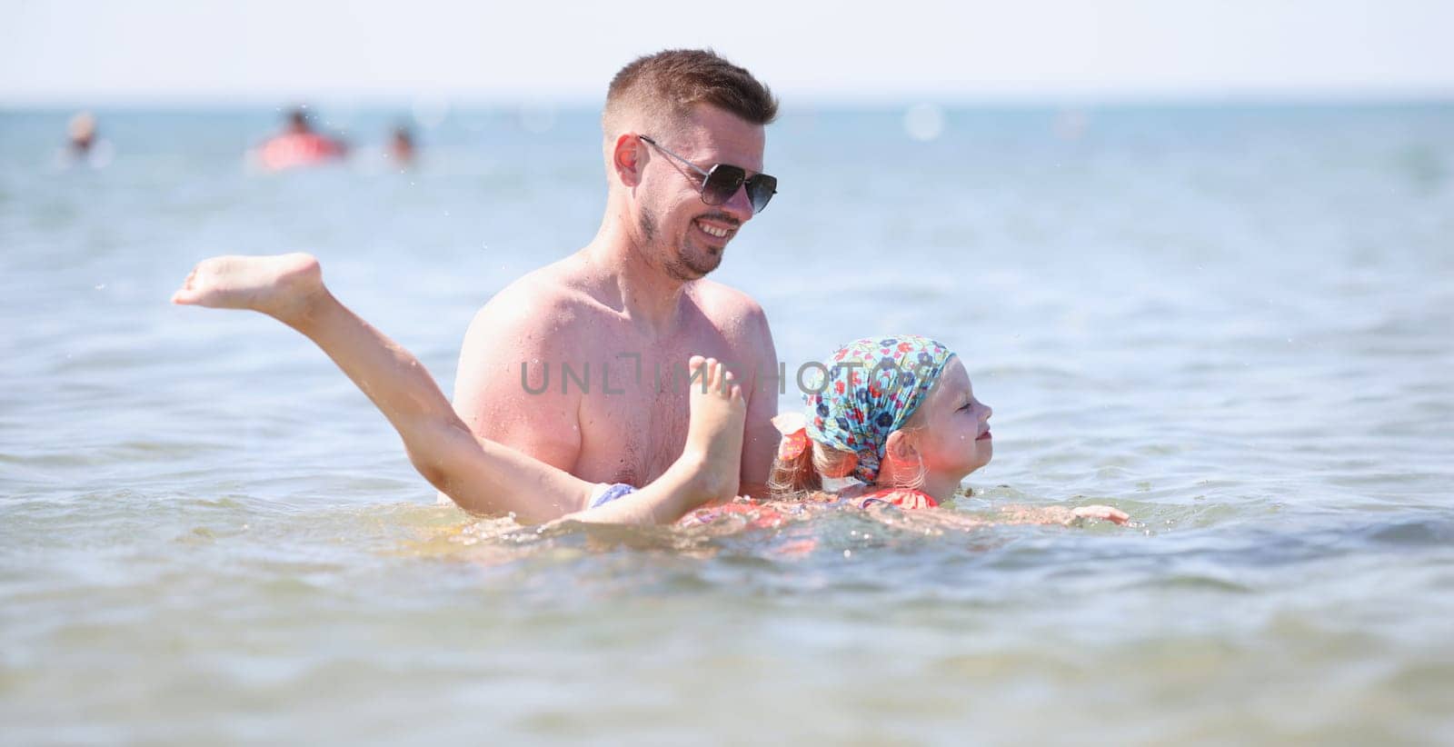Dad teaches girl to swim at sea. Vacation at sea with children concept