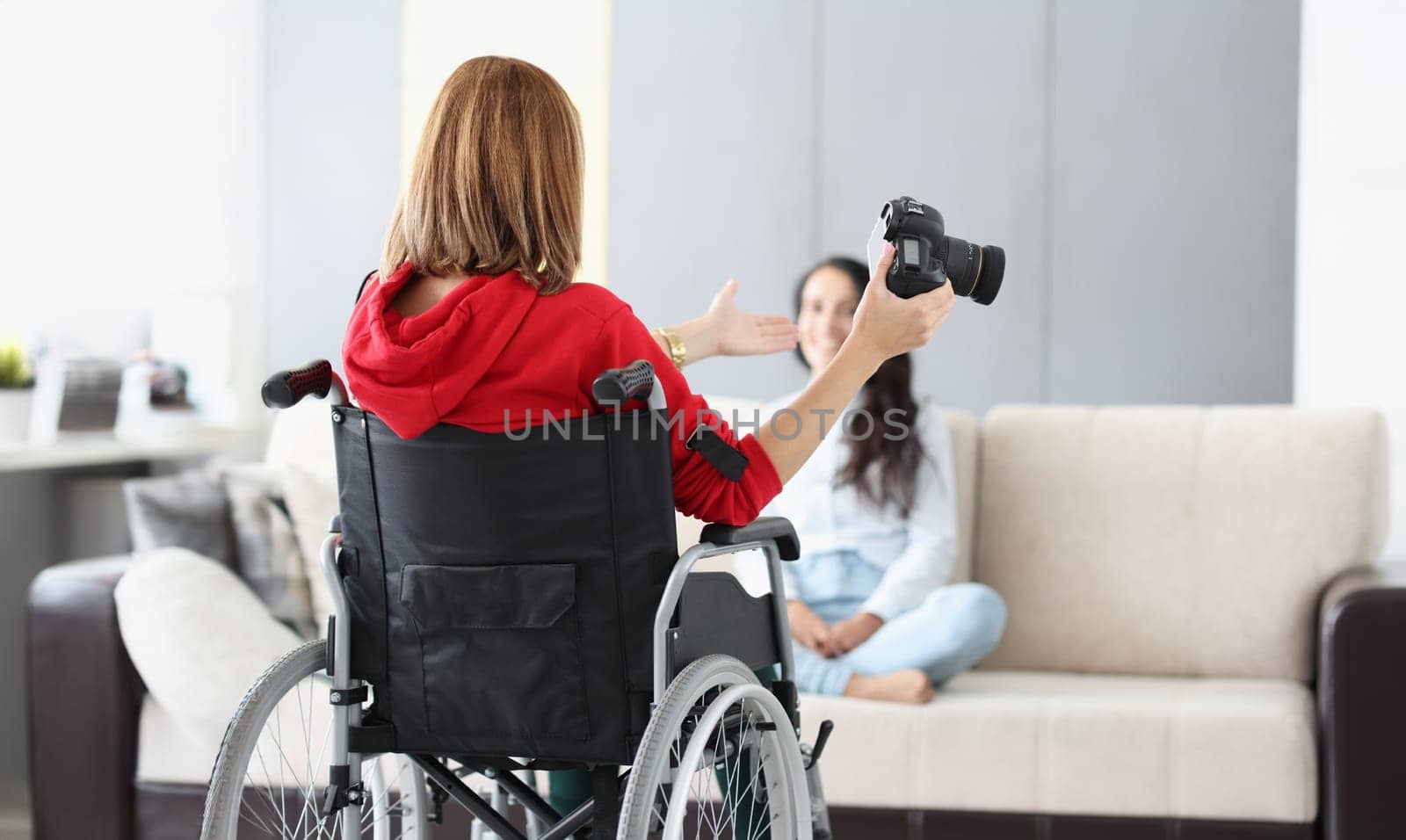 Woman in wheelchair with camera conducts home photo session. Professions for people with disabilities concept