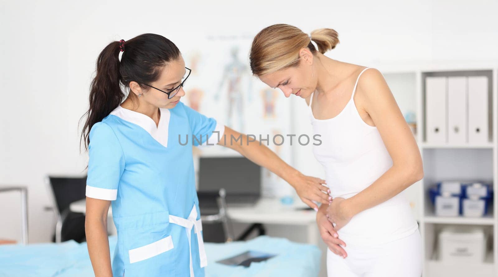 Doctor provides medical assistance to woman with abdominal pain. Pain syndromes in the intestinal area concept