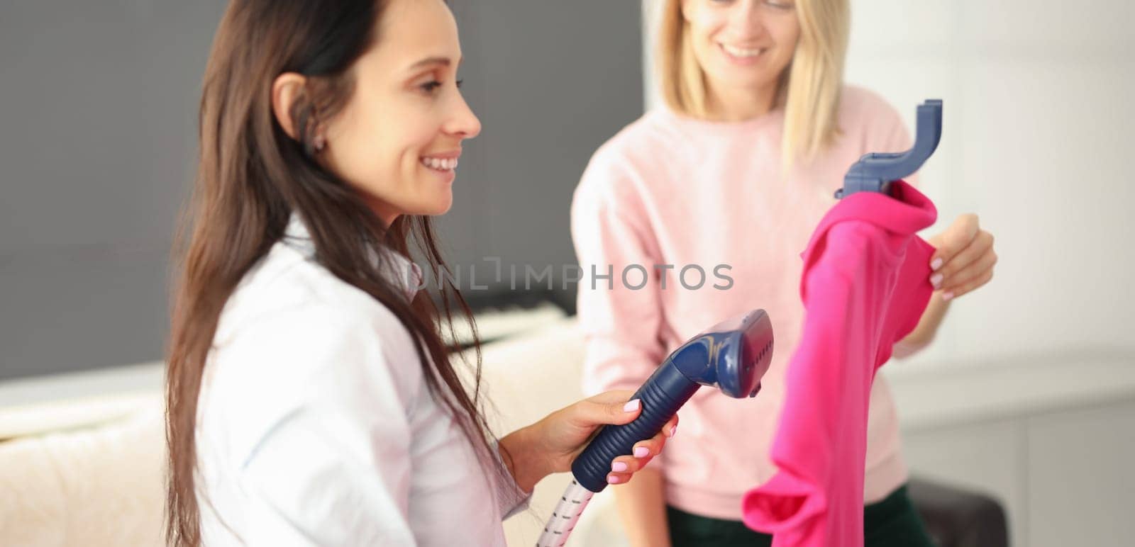 Woman ironing things with steam steamer at home. Ironing technology concept