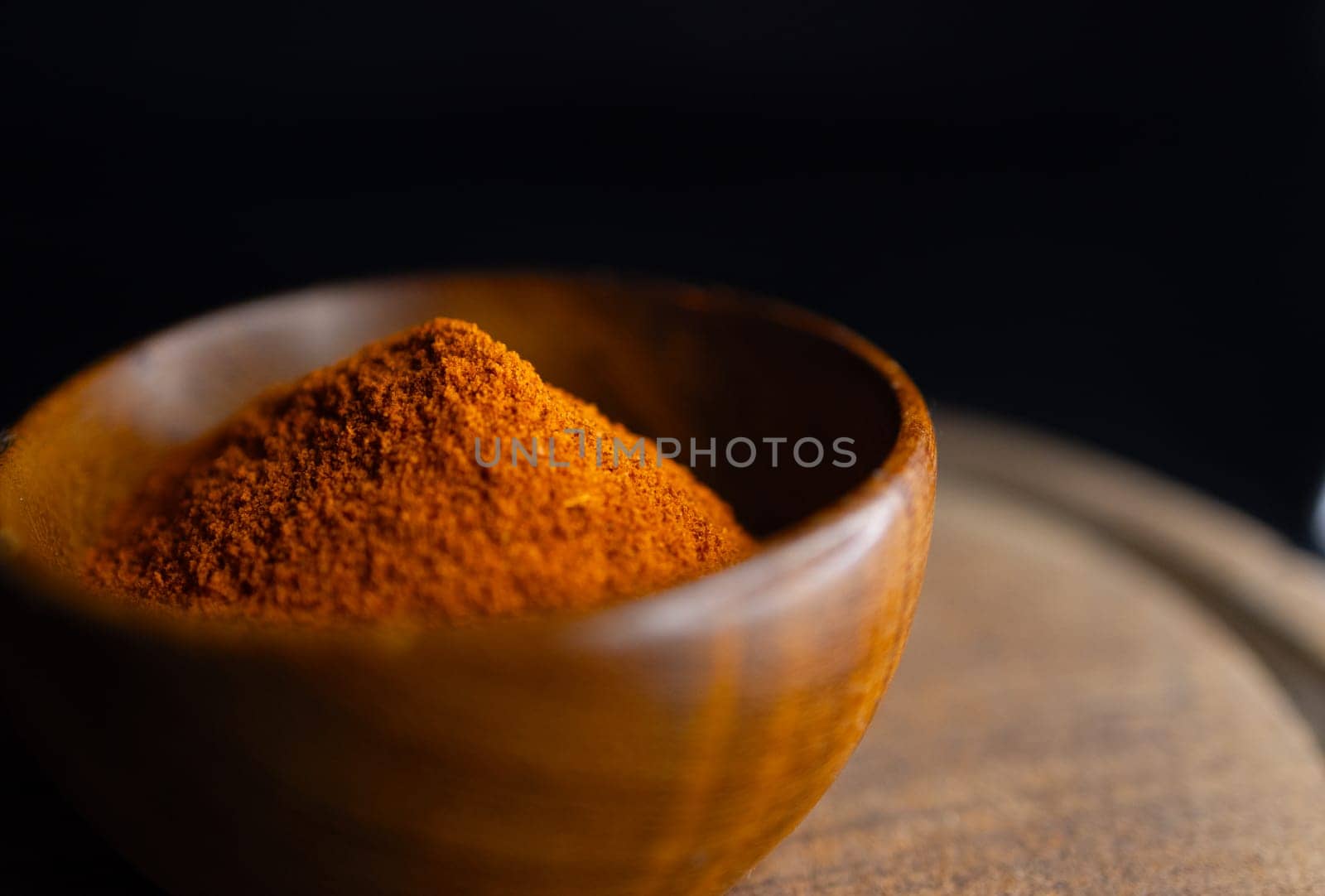 Very close up view of Red paprika powder on a wooden bowl by VeroDibe