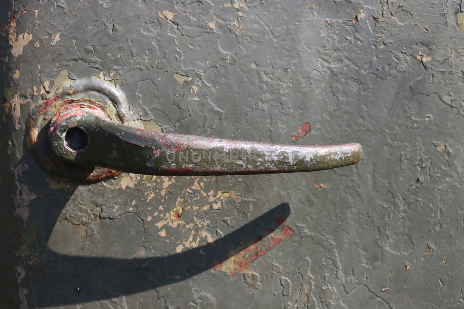 Old green rusty metal door handle, closeup of photo.