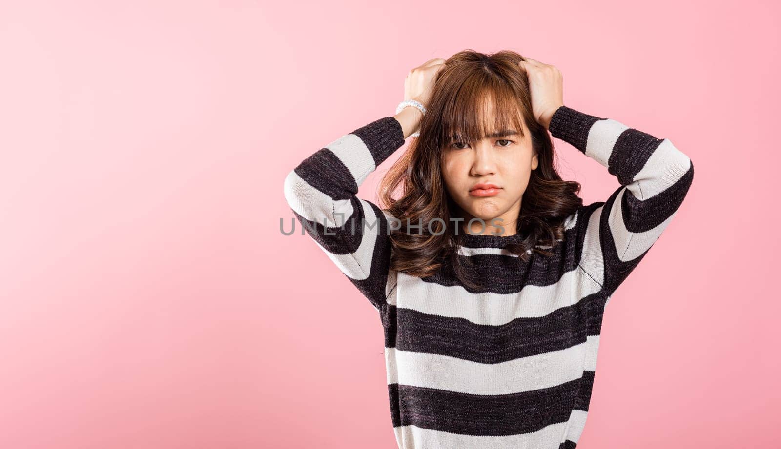 Asian happy portrait beautiful cute young woman standing angry and mad raising fist frustrated and furious while shouting with anger isolated, studio shot on pink background and copy space