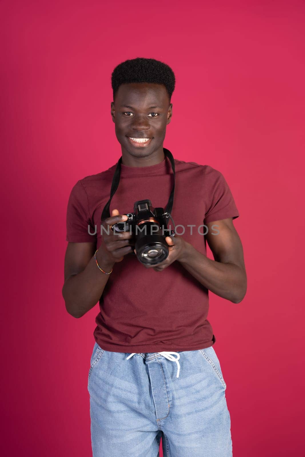 A man with a camera is smiling and holding the camera up to his face. The image has a happy and lighthearted mood, as the man is enjoying himself while taking a photo