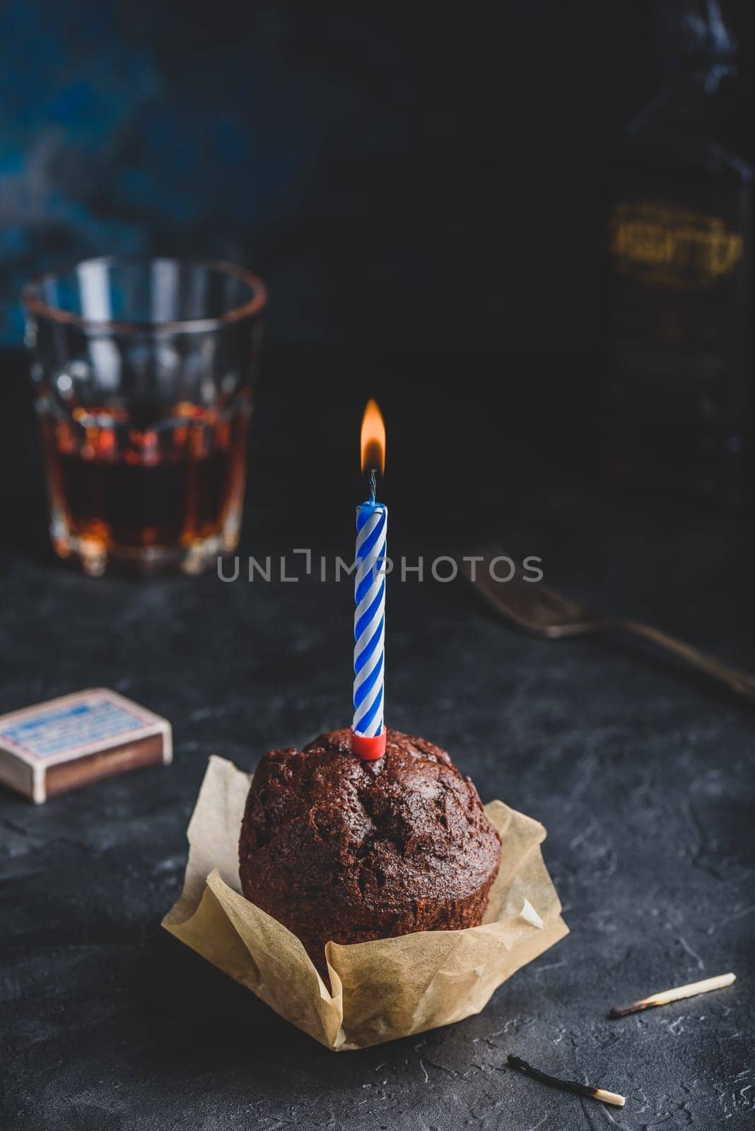 Chocolate muffin with birthday candle on dark concrete background