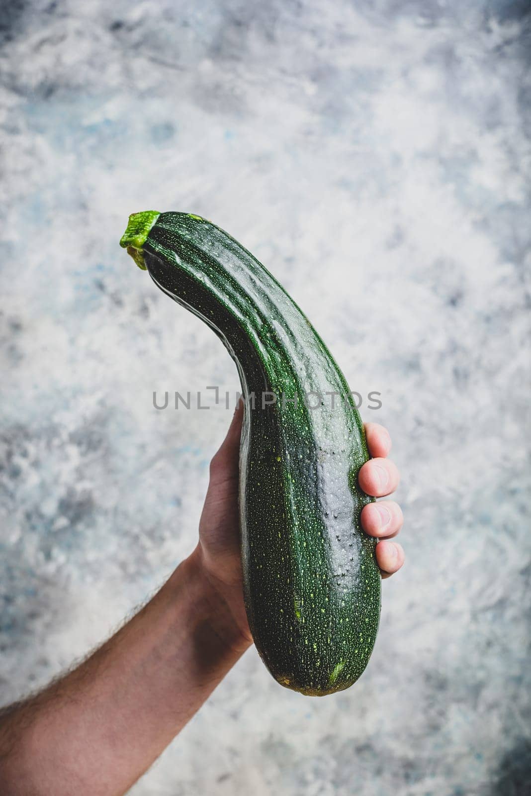 Male hand holding fresh organic zucchini